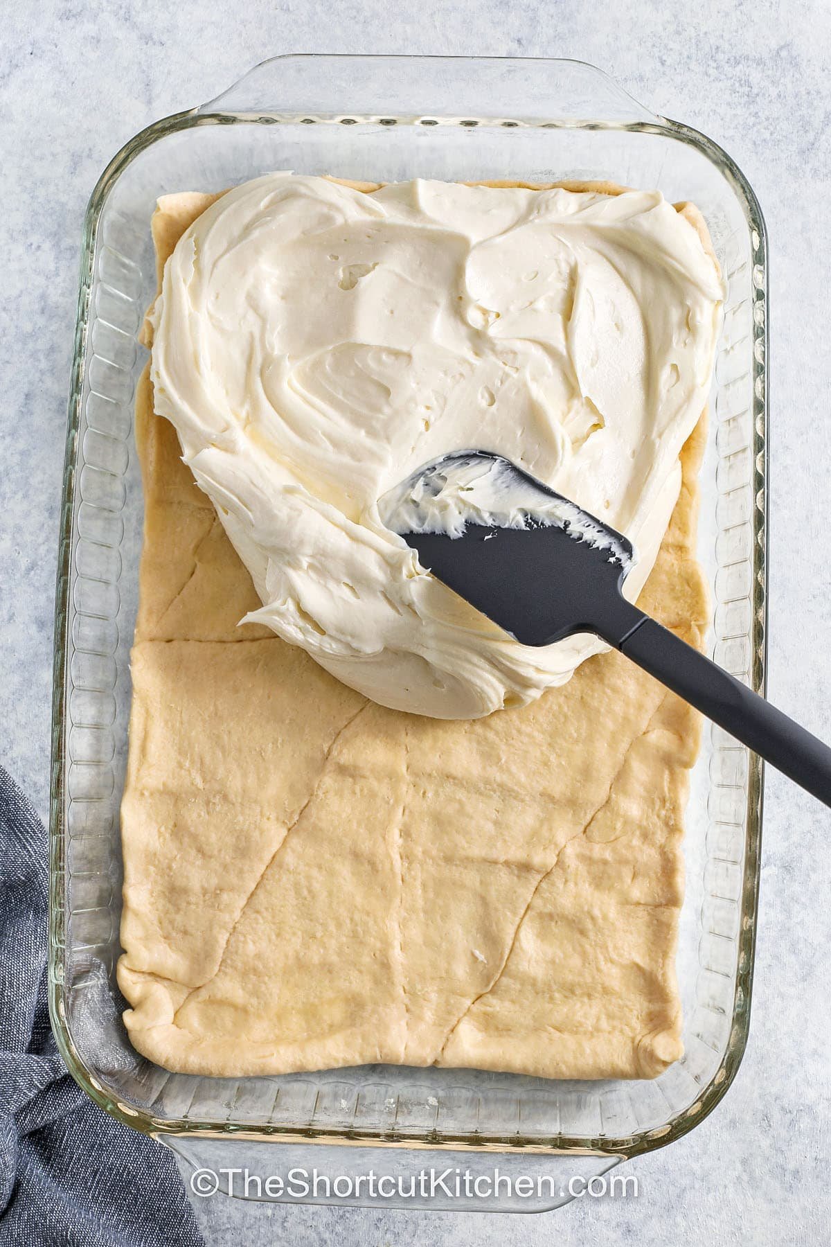 adding cream cheese filling to crescent roll dough to make Cream Cheese Squares