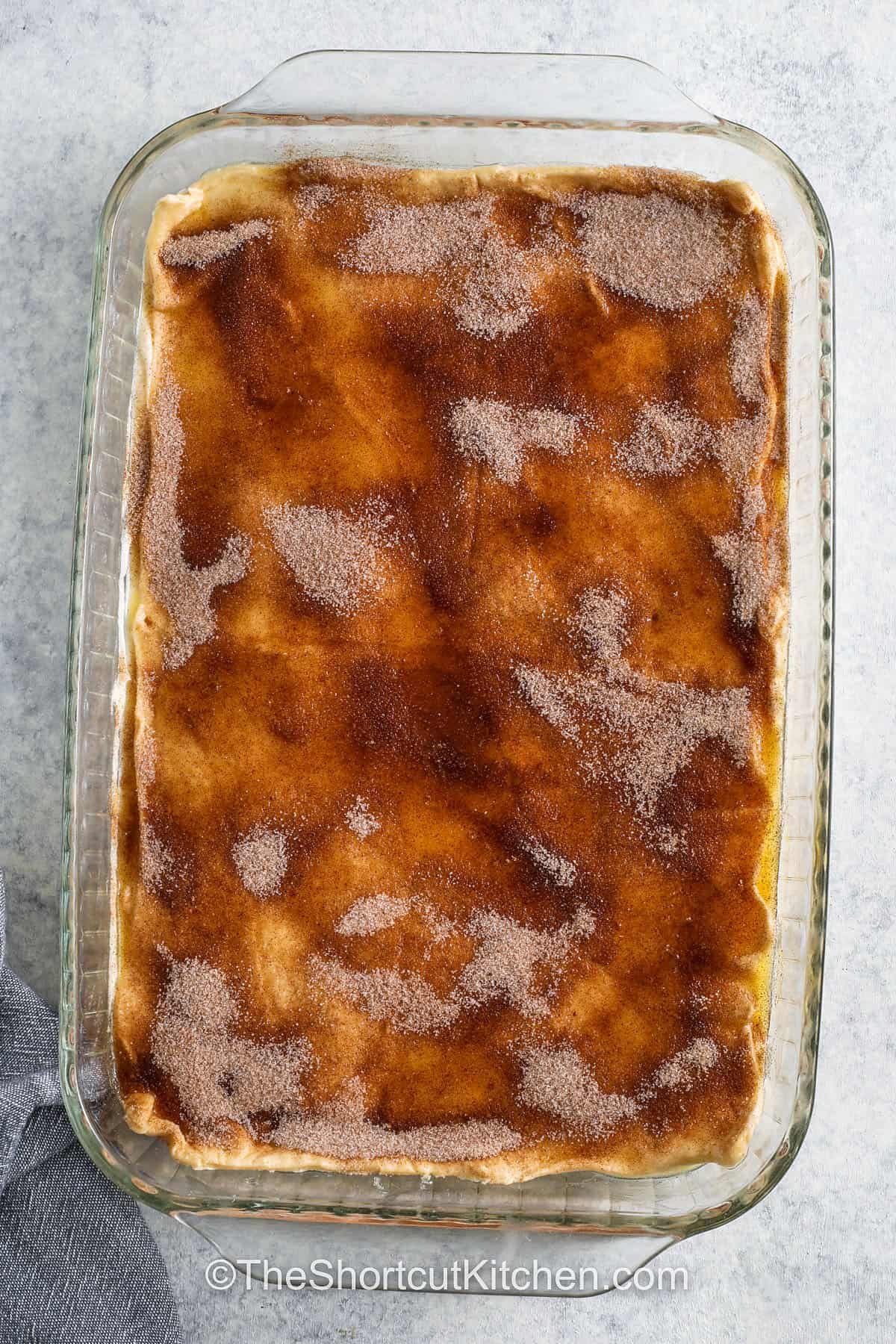 adding cinnamon sugar topping to Cream Cheese Squares in dish