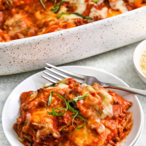 plated cheesy Frozen Ravioli Bake with casserole dish full in the background