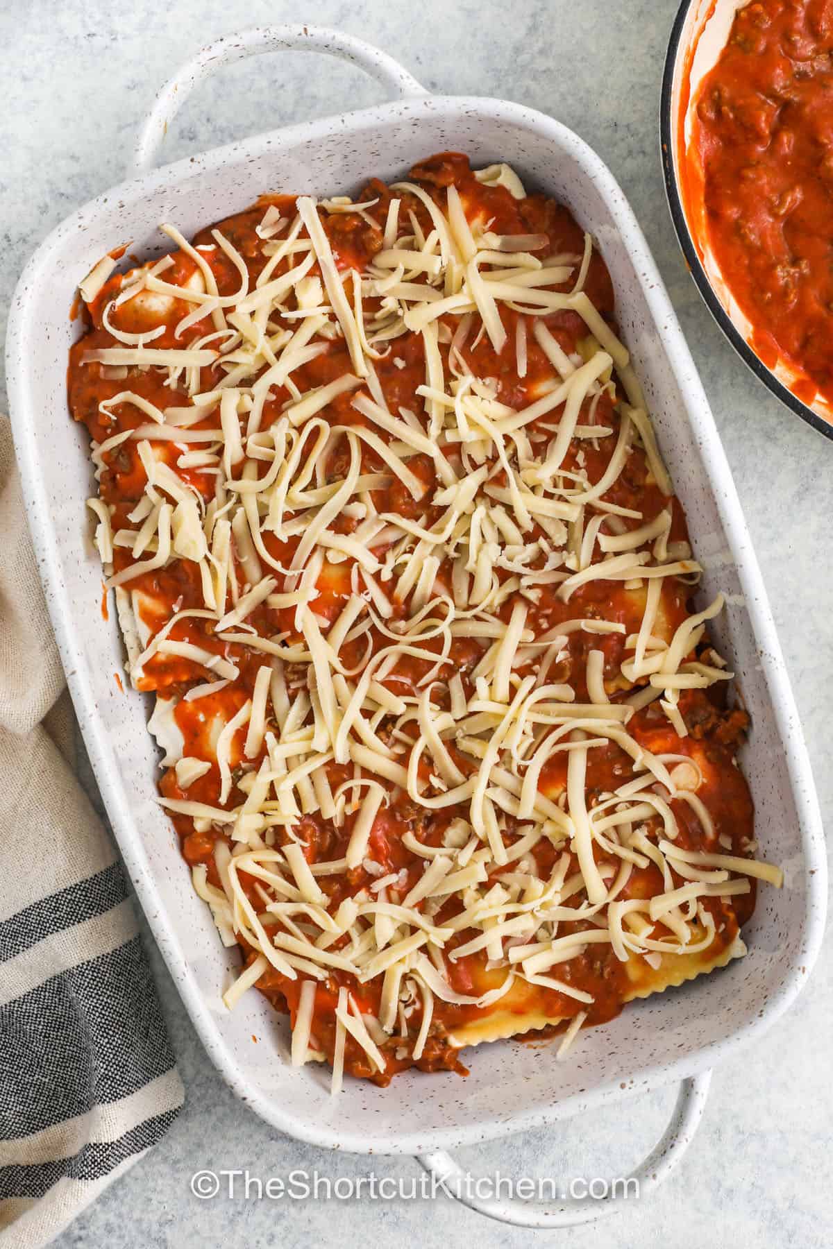 adding another layer of meat sauce and a layer of cheese to the casserole dish to make Frozen Ravioli Bake