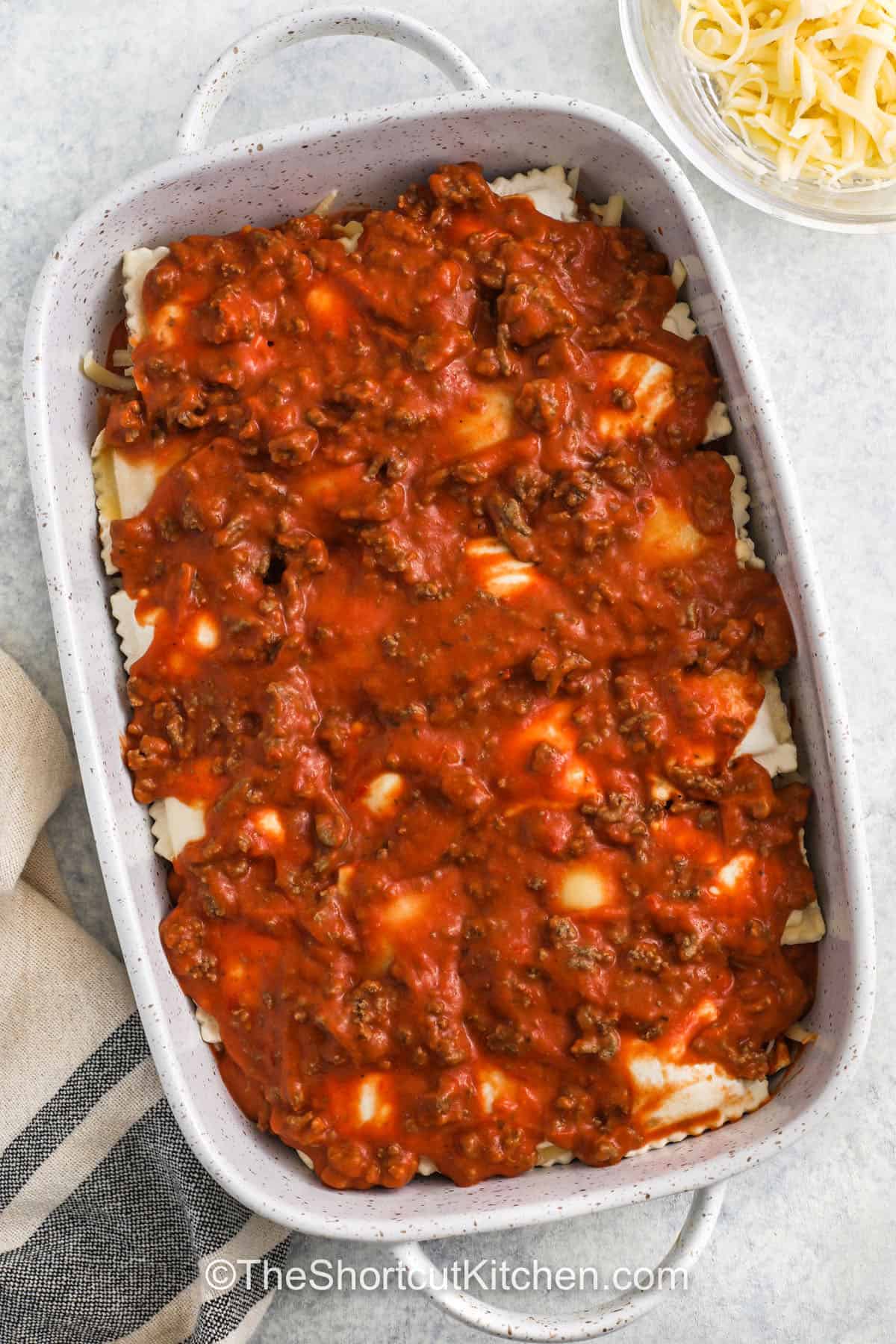 adding another layer of ravioli and meat sauce to the casserole dish to make Frozen Ravioli Bake