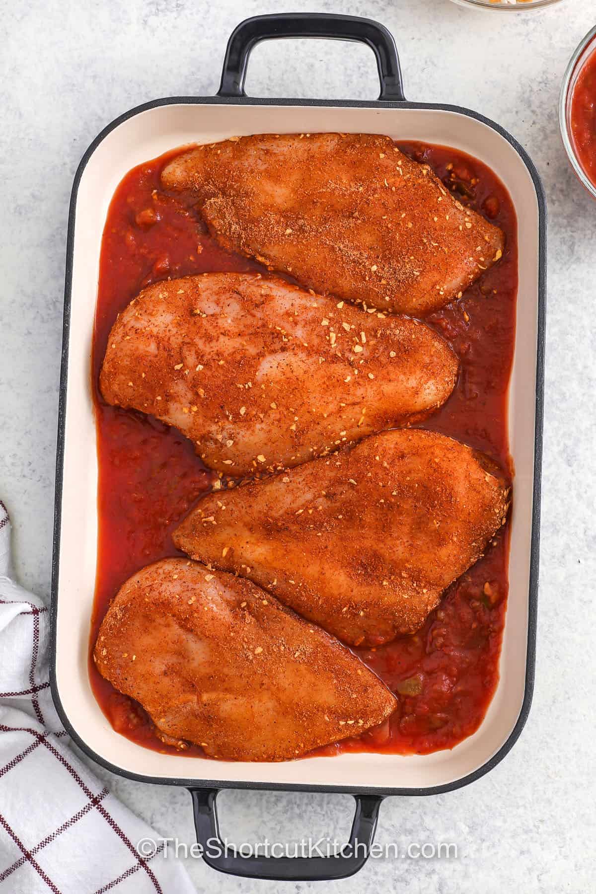 adding seasoned chicken to salsa in dish to make Baked Salsa Chicken