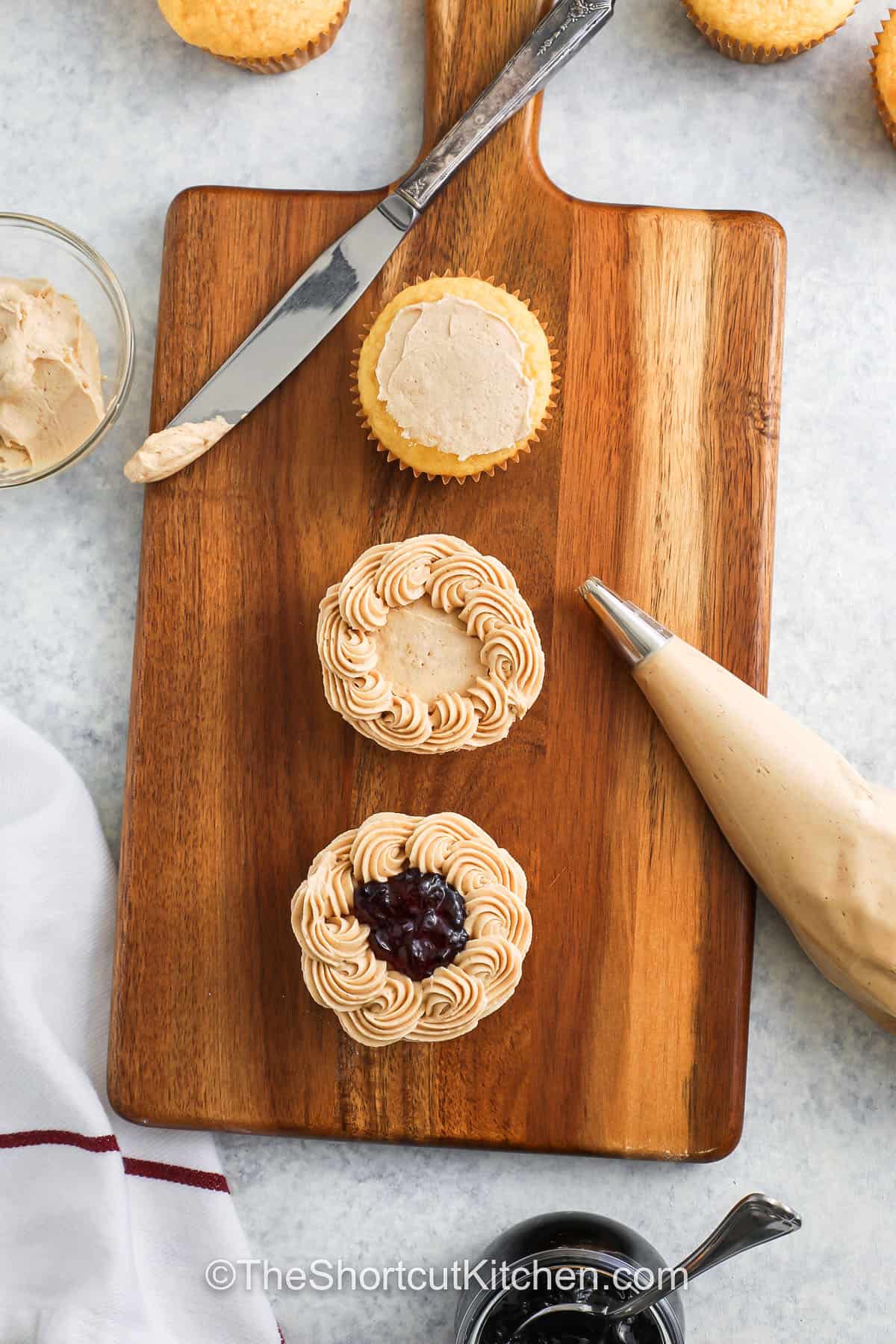 adding frosting and jelly to Peanut Butter Cupcakes