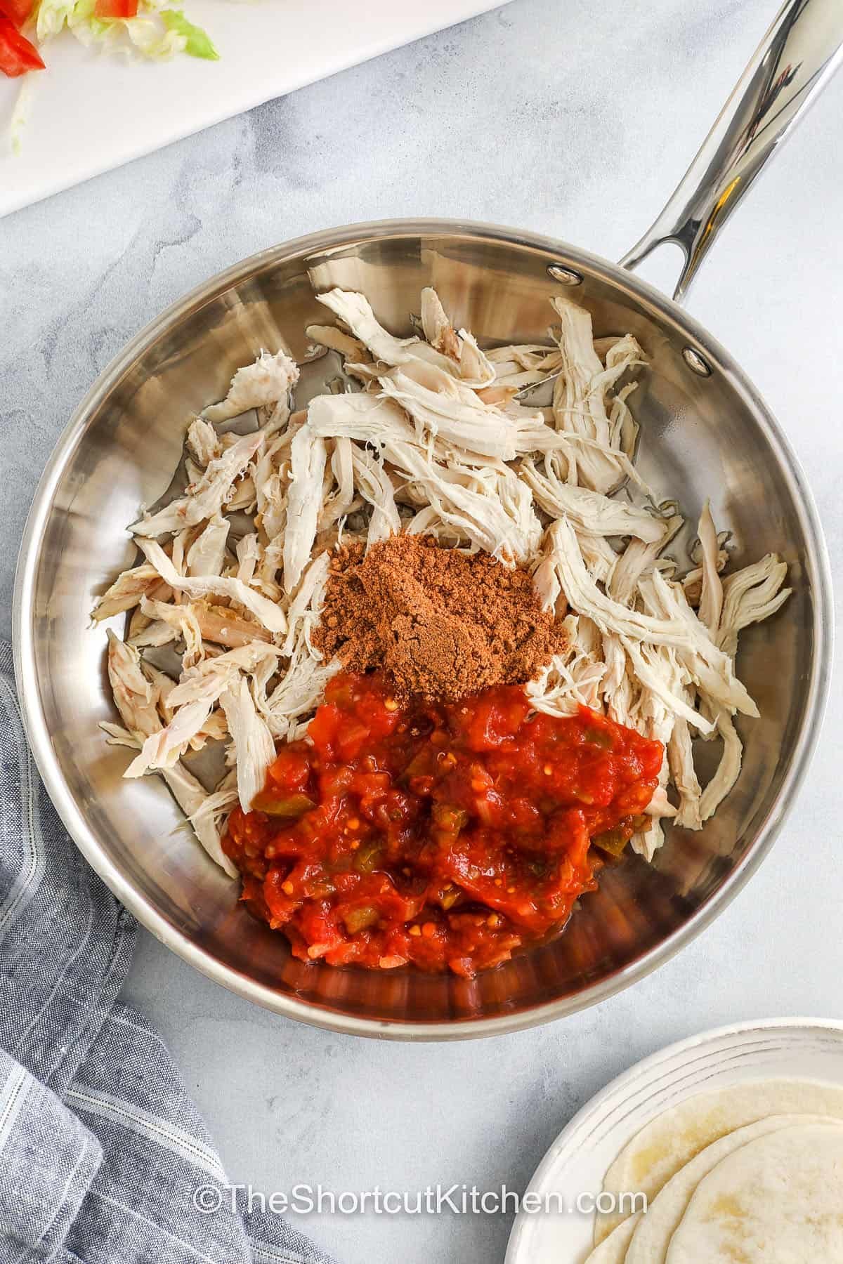 adding seasoning and salsa to chicken to make Rotisserie Chicken Tacos