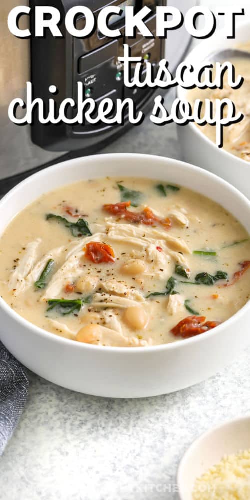 Tuscan chicken soup is full of rich, hearty flavors thanks to a creamy base, shredded chicken, white beans, and spinach. Sun dried tomatoes add a burst of savory goodness while garlic and Italian seasoning tie all the flavors together. Made in the slow cooker, this easy recipe is perfect for a cozy dinner that tastes like it came from a rustic Italian kitchen. #theshortcutkitchen close up of creamy Crockpot Tuscan Chicken Soup with a title