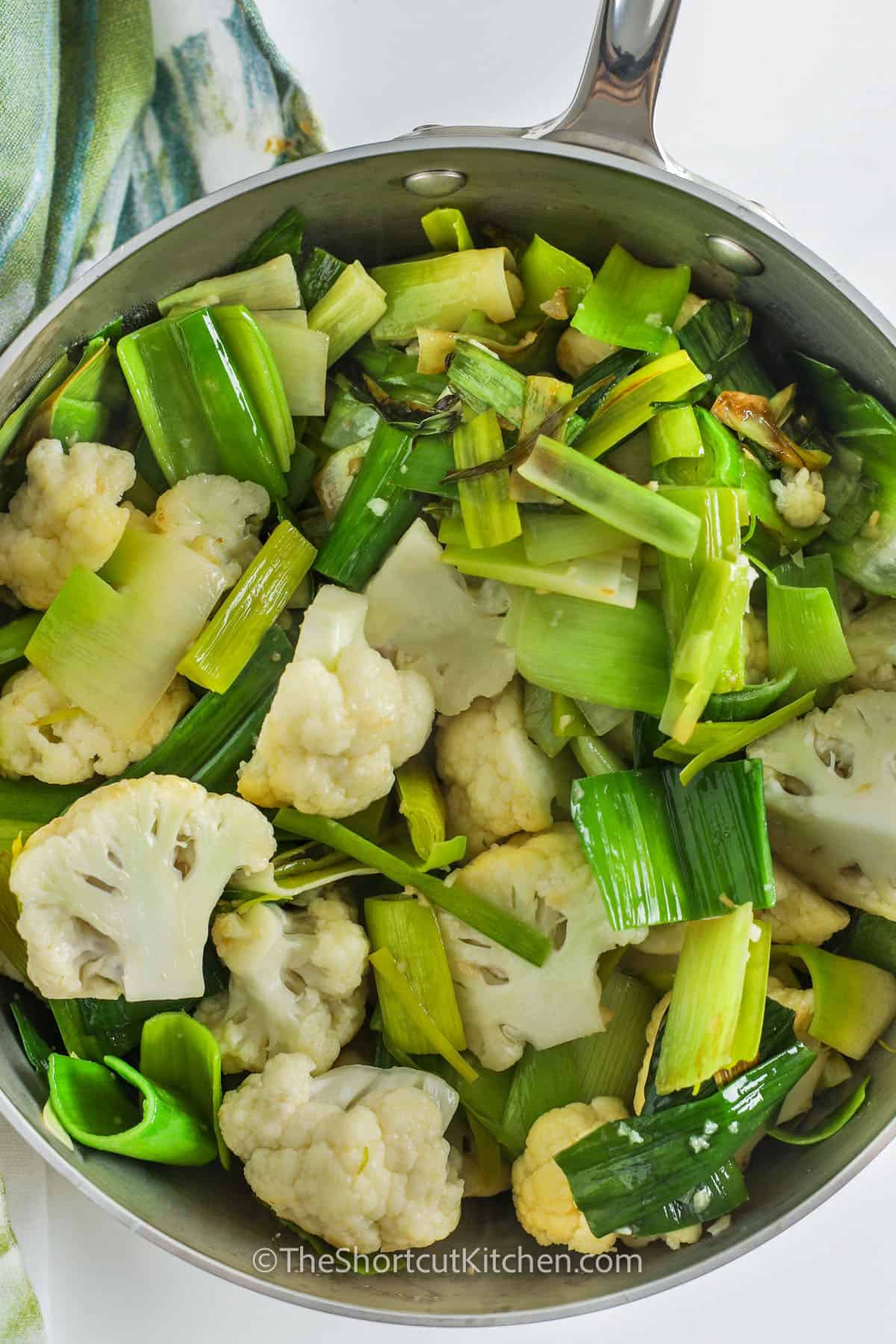 Creamy and comforting, this cauliflower leek soup is made with real ingredients and comes together quickly in just one pot. The garlic, butter, and olive oil provide depth, while the simmered cauliflower and leeks offer a hearty base. An immersion blender creates a silky finish, and a bit of cream rounds it out. It’s a perfect weeknight dish or a cozy weekend treat. #theshortcutkitchen cooked cauliflower and leeks in a pot to make Cauliflower Leek Soup