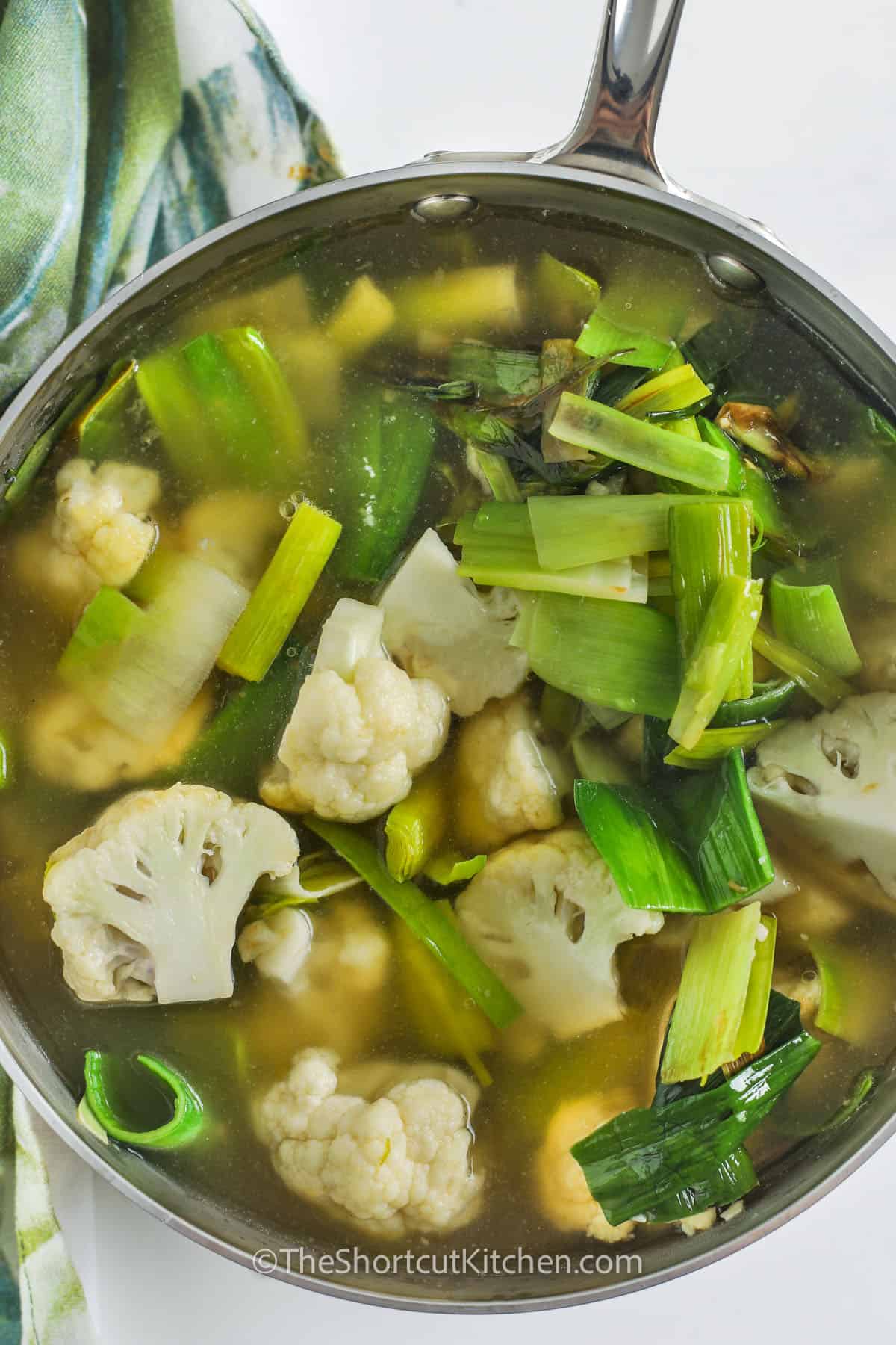This Cauliflower Leek Soup is so creamy, smooth, and flavorful. It is a paleo favorite, that can easily be made at home and in just one pot! Using simple ingredients like cauliflower, leeks, butter, chicken broth, and cream, then cooked and blended in just a few steps, this soup will be ready to serve. Delicious as an appetizer, for lunch, or serve with a hearty salad for a filling dinner. #theshortcutkitchen ingredients in pot to make Cauliflower Leek Soup