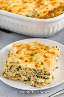cheesy Chicken Alfredo Lasagna Recipe on a plate with casserole dish full