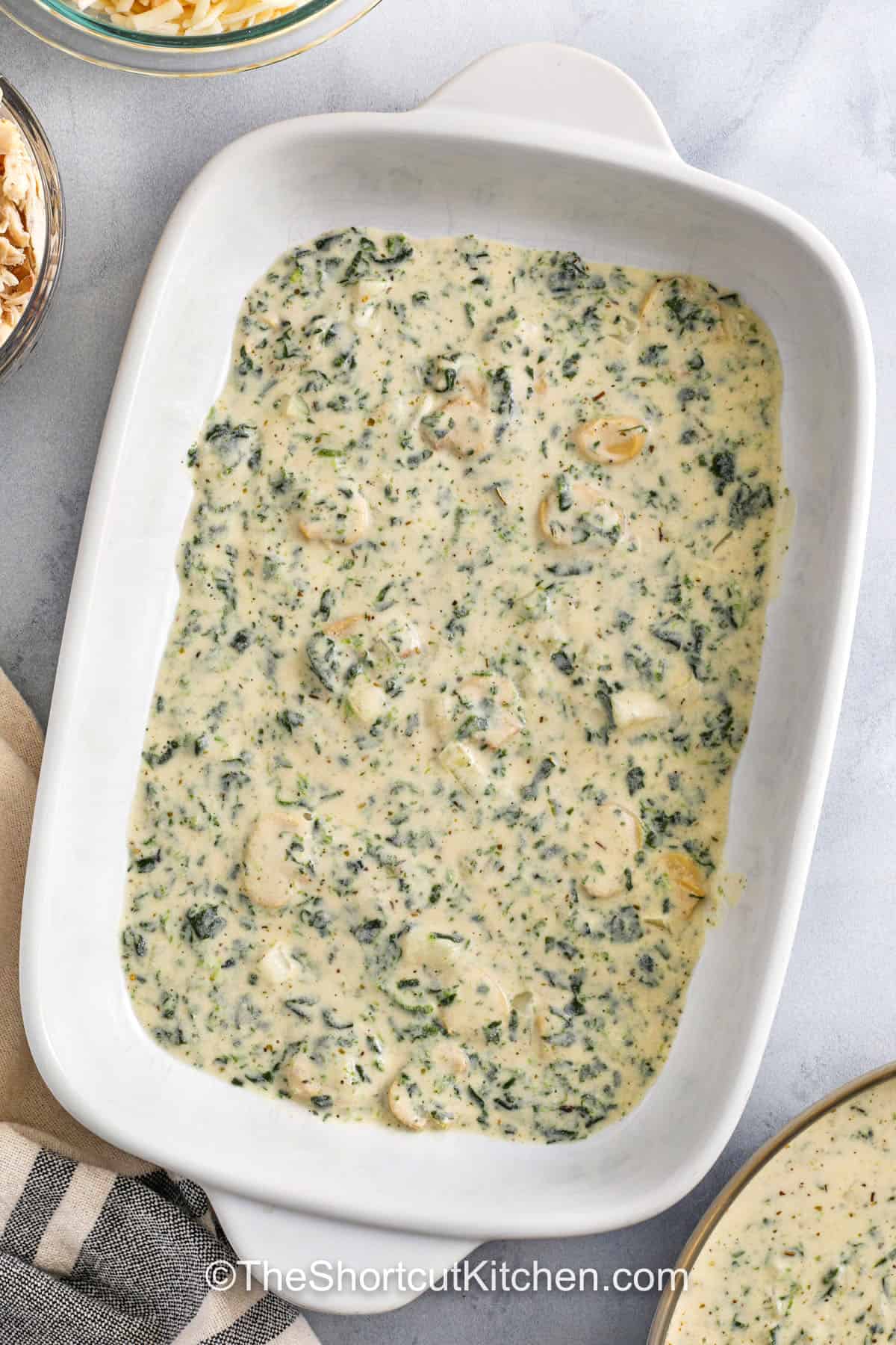 adding sauce to casserole dish to make Chicken Alfredo Lasagna Recipe
