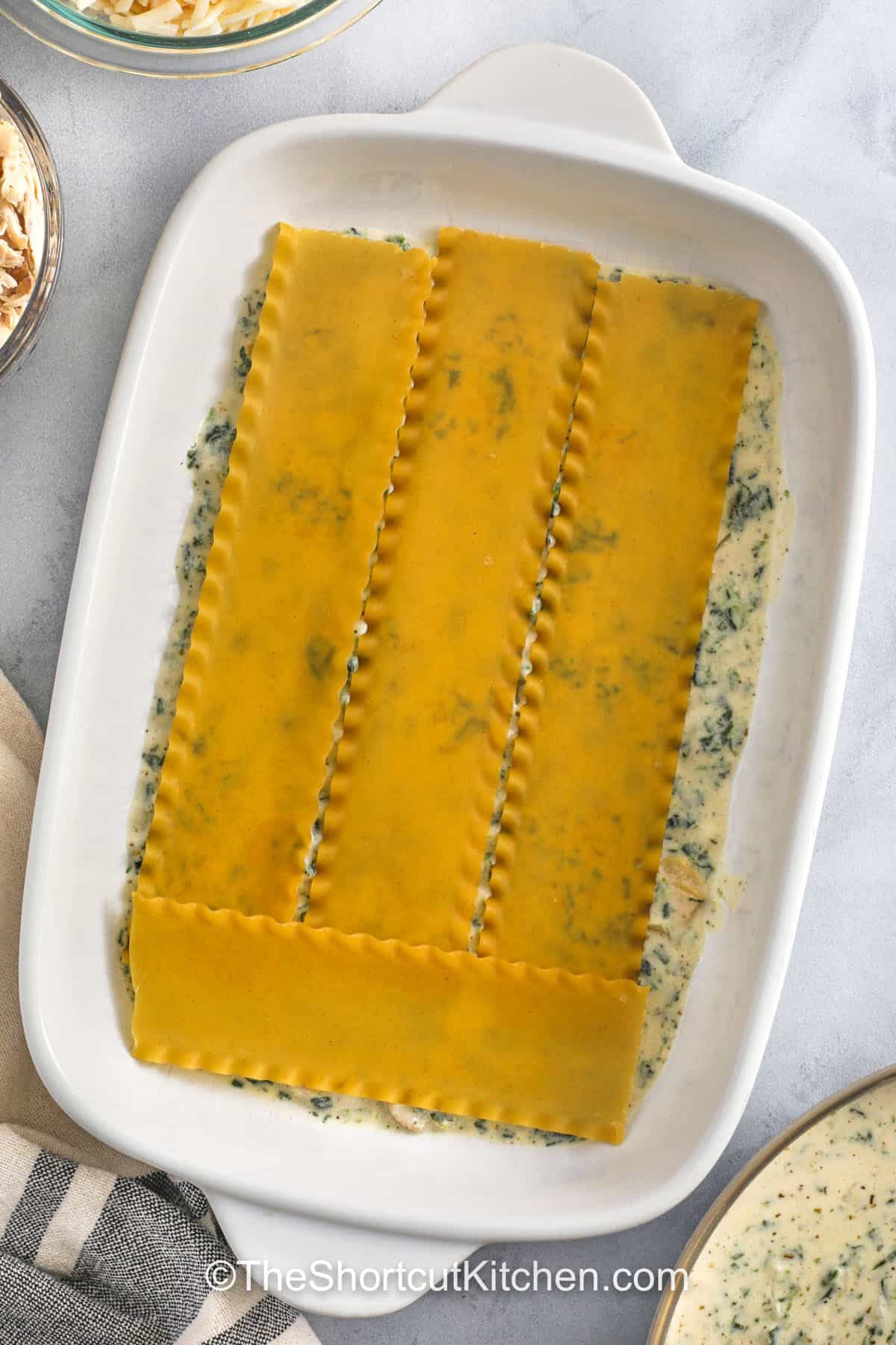 adding lasagna noodles to dish to make Chicken Alfredo Lasagna Recipe