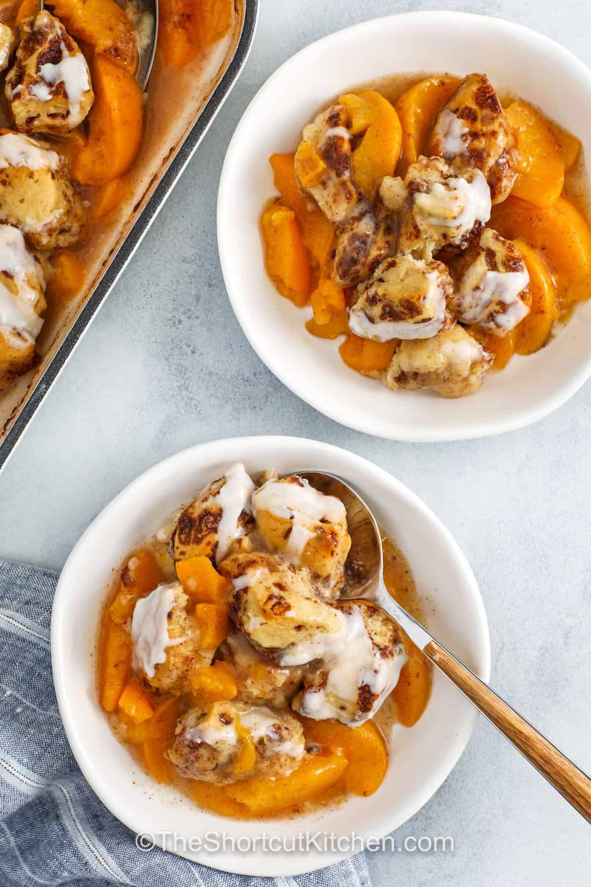 top view of Cinnamon Roll Peach Cobbler in bowls with a spoon