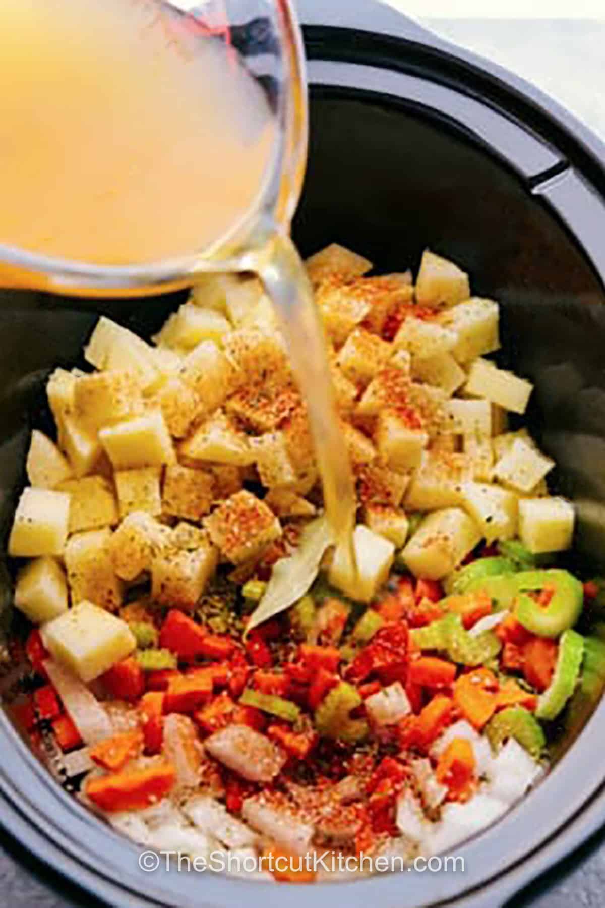 adding broth to ingredients in crockpot to make Crockpot Corn Chowder