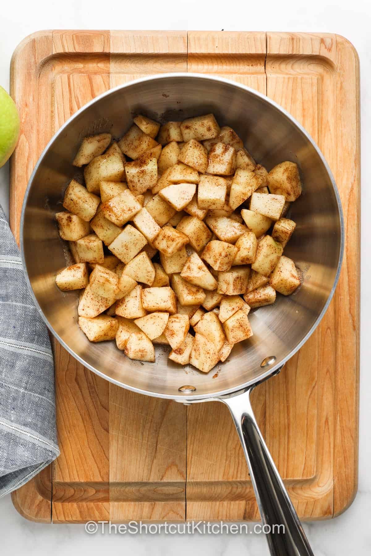 This easy apple pie filling is perfect for quick homemade desserts and pastries. Made from scratch with fresh apples, sugar, and warm spices, it comes together on the stovetop in minutes. The simple blend of flavors with a touch of butter makes it rich and cozy. Make it ahead to refrigerate or freeze, so you’re always ready for your favorite treats. #theshortcutkitchen adding spices to apples to make Easy Apple Pie Filling