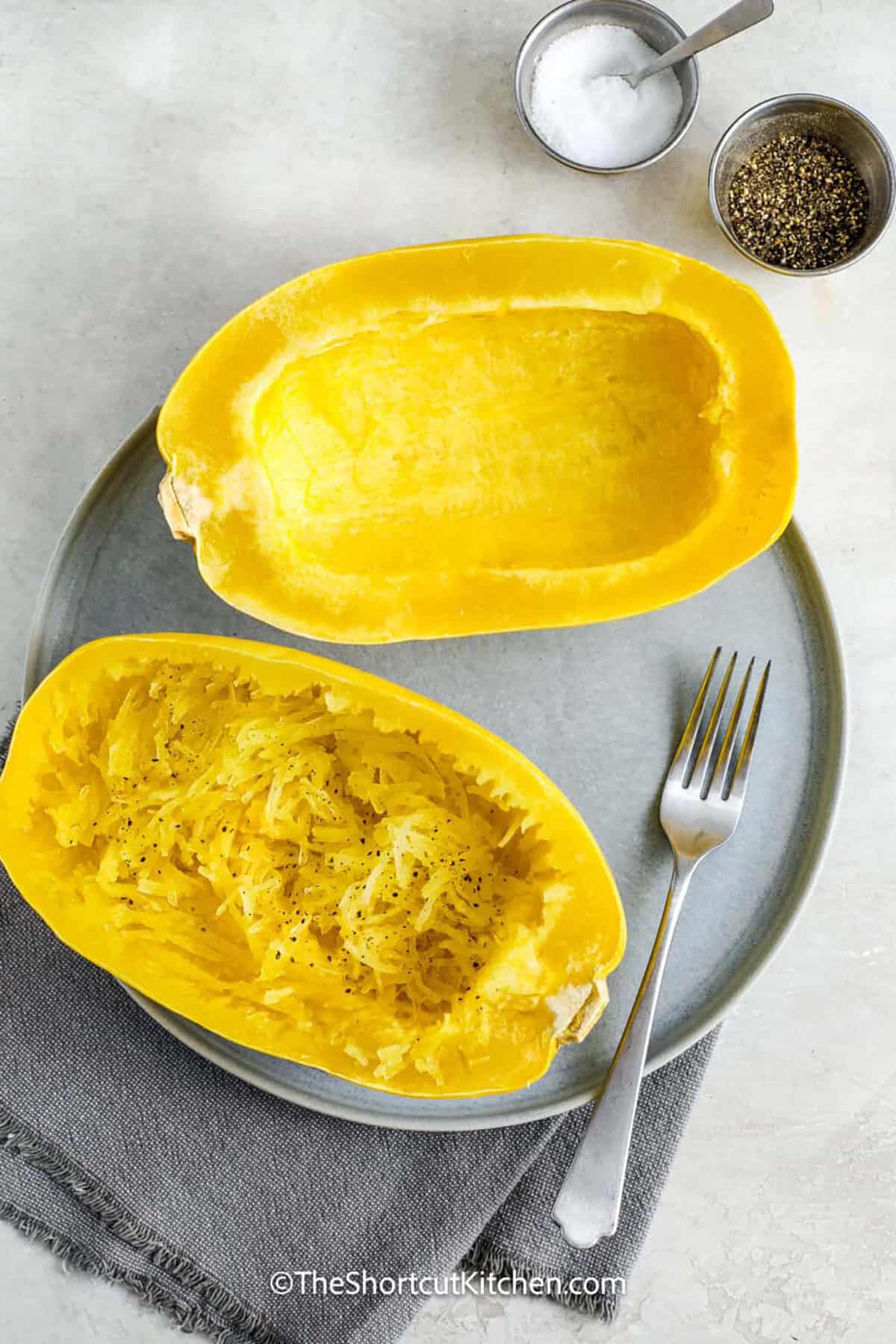 This recipe for microwave spaghetti squash is the best way to cook a simple and tasty low-carb noodle substitute. With this recipe, you can learn how to prep the squash by cutting it into halves and letting the microwave do the work. The result is tender strands that are easy to season or serve with your favorite toppings. You do not need the oven to make a quick and healthy side dish. It is one of the easiest ways to enjoy this veggie. #theshortcutkitchen Microwave Spaghetti Squash on a plate