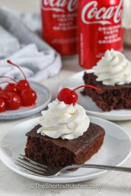 plated slice of Cake Mix Soda Cake with whipped cream and a cherry on top