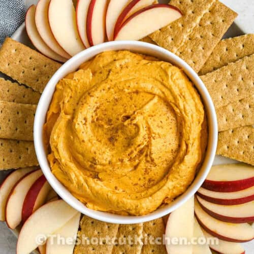 pumpkin dip in a bowl with crackers and apple slices around the bowl as dippers