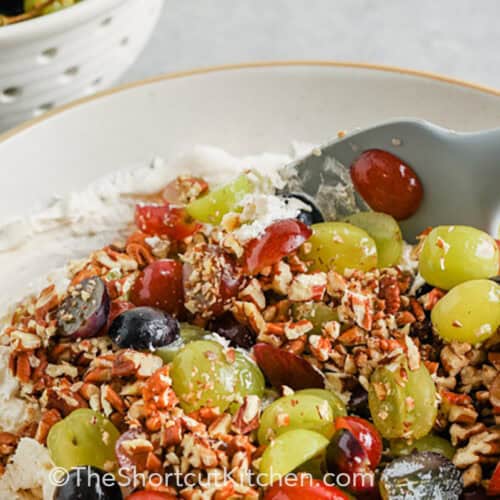 spoon stirring a bowl of grape salad