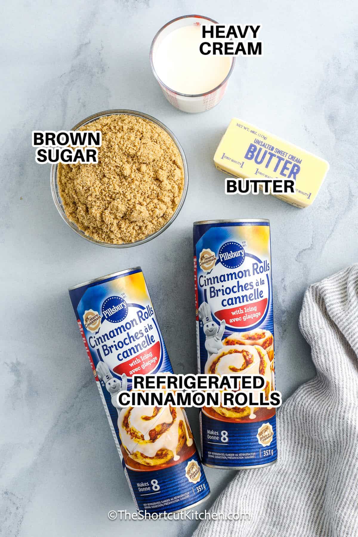Cinnamon roll monkey bread is the ultimate sweet, gooey treat that’s shockingly easy to make. Start with store-bought cinnamon rolls and toss them in a quick caramel sauce of butter, brown sugar, and cream. Bake until golden, then drizzle with icing for a sticky, glazed, pull-apart delight. Great for breakfast, holiday brunches, or anytime you want something indulgent and satisfying. One of the best shortcut desserts you can whip up fast! #theshortcutkitchen Ingredients to make cinnamon roll monkey bread labeled: heavy cream, butter, brown sugar, and refrigerated cinnamon rolls