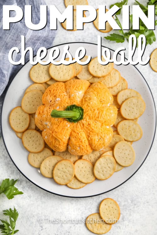 Pumpkin cheese ball on a plate with crackers and writing