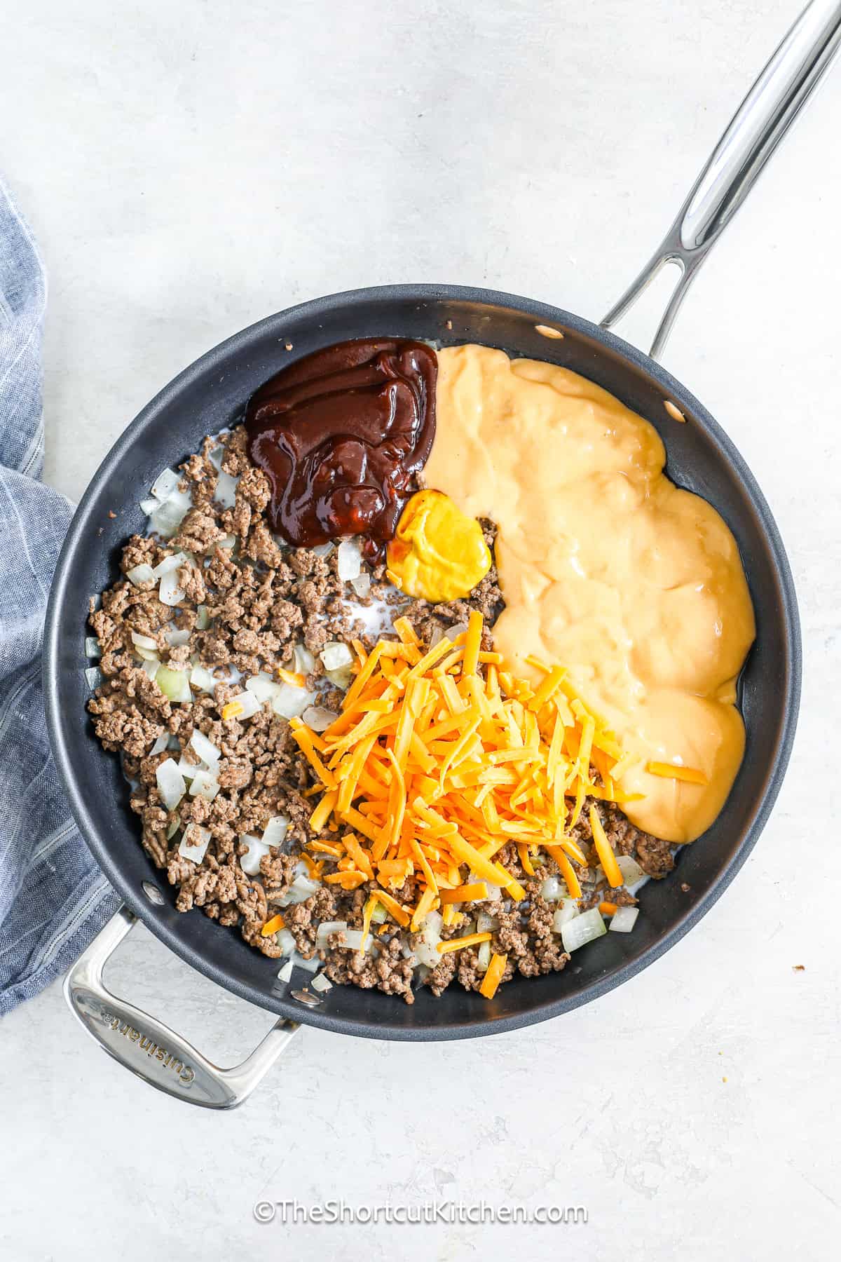 This cheeseburger tater tot casserole combines all your favorite burger flavors in a one-pan, easy-to-make meal, with seasoned ground beef, diced onions, creamy cheddar sauce, shredded cheddar, and a crispy tater tot topping. Bake it until golden and bubbling, then add pickles if you like, and serve a dish that’s fun, satisfying, and full of classic cheeseburger comfort in every cheesy, crunchy bite. #theshortcutkitchen Ingredients to make Cheeseburger Tater Tot Casserole combined in a sauce pan