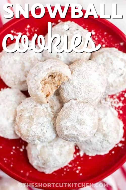 This snowball cookies recipe combines soft butter, powdered sugar, vanilla, flour, and pecans to form tender little cookie rounds that bake up barely golden. A generous dusting of powdered sugar adds the signature snowy look and sweet finish. These cookies require no chilling, mix easily by hand or mixer, and stay delicious for days, making them ideal for gifting, holidays, or cozy winter baking. #theshortcutkitchen snowball cookies on a red plate with writing