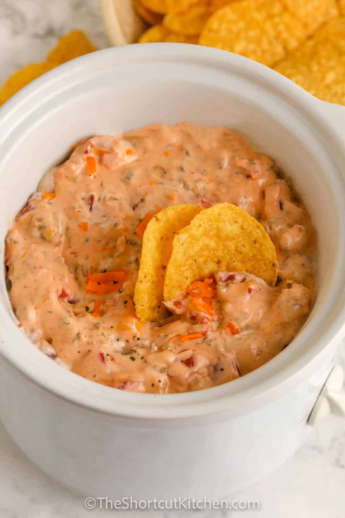 Cream cheese Rotel dip is the ultimate slow cooker appetizer with sausage, cream cheese, and Rotel tomatoes with chilies. Brown the meat, dump everything in the crockpot, and stir as it melts into a creamy, zesty dip. Customize with sharp cheddar, jalapeños, bacon, or cilantro. Perfect for game day, potlucks, and holiday parties with sturdy tortilla chips or Fritos. #theshortcutkitchen Cream Cheese Rotel Dip Recipe in the pot with chips