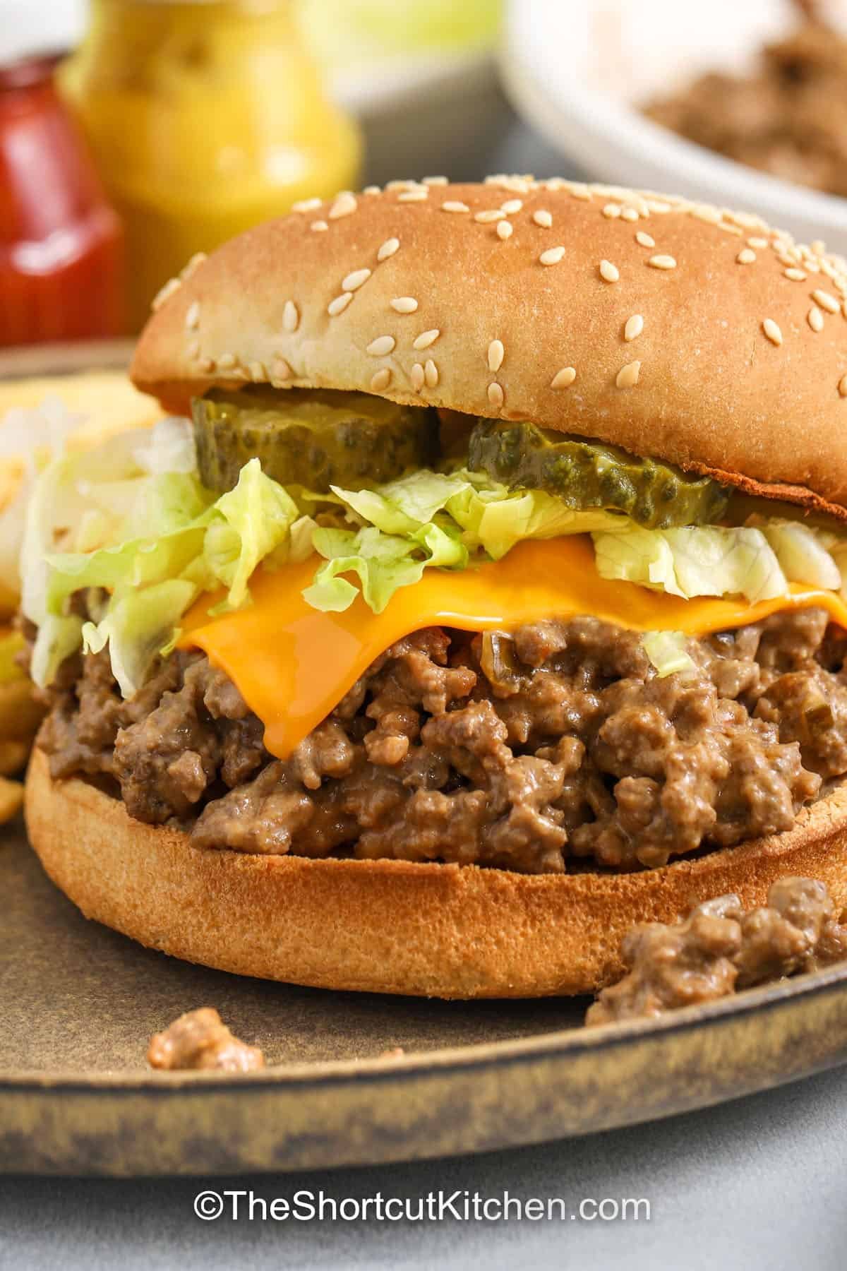 Big Mac Sloppy Joes are messy, saucy, and loaded with burger flavor. Brown ground beef, drain well, then stir in Thousand Island dressing, onion powder, mustard, and ketchup. Simmer briefly and serve on hamburger buns with pickles, shredded lettuce, and American cheese. These cheeseburger sloppy joes are a simple, kid-friendly dinner idea. #theshortcutkitchen big mac sloppy joes on a plate