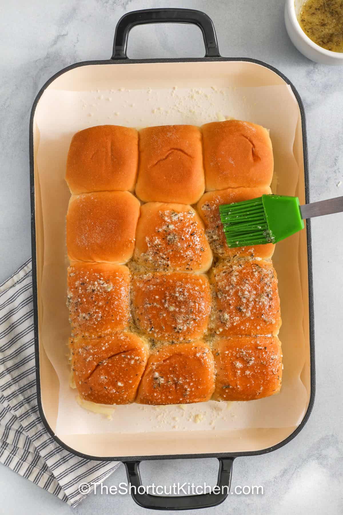 Hawaiian roll chicken parm sliders bring big comfort fast. Use frozen chicken tenders or nuggets, jarred marinara sauce, and shredded mozzarella for a true shortcut meal. Brush the rolls with garlic butter and parmesan, bake until bubbly, and serve with extra marinara. Perfect baked chicken parm sliders for family dinners, tailgates, and potlucks. #theshortcutkitchen chicken parm sliders brushed with garlic butter