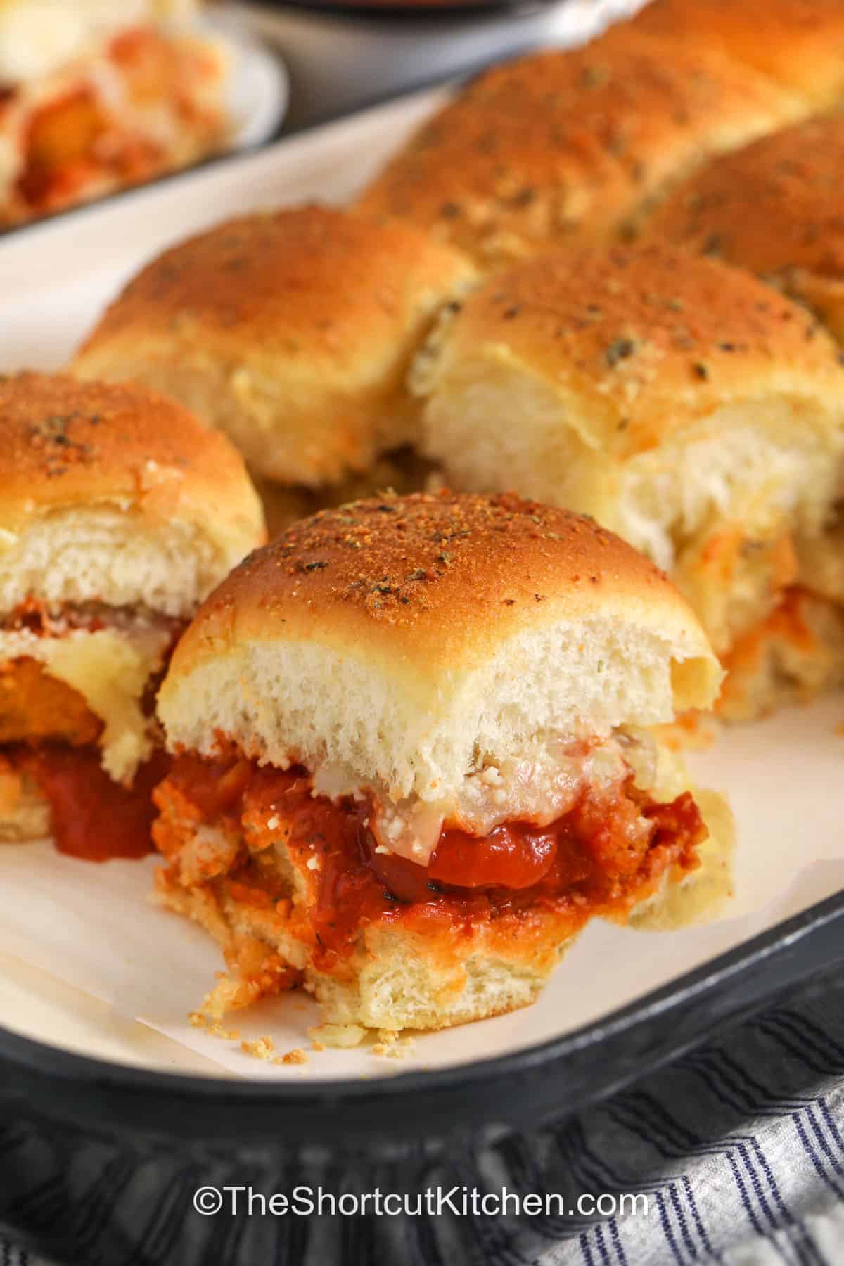 Make easy chicken parm sliders in one pan. Bake frozen chicken nuggets until crispy, then layer with marinara and mozzarella on sweet Hawaiian rolls. Finish with a buttery garlic-parmesan topping and bake until golden. These chicken nugget parmesan sliders are cheesy, saucy, and made for sharing, plus they reheat well for quick lunches and leftovers. #theshortcutkitchen chicken parm sliders in a pan