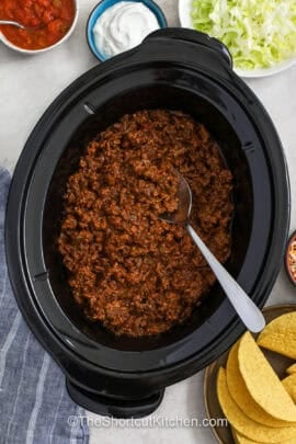 Crockpot Taco Meat in the crock pot with toppings around it
