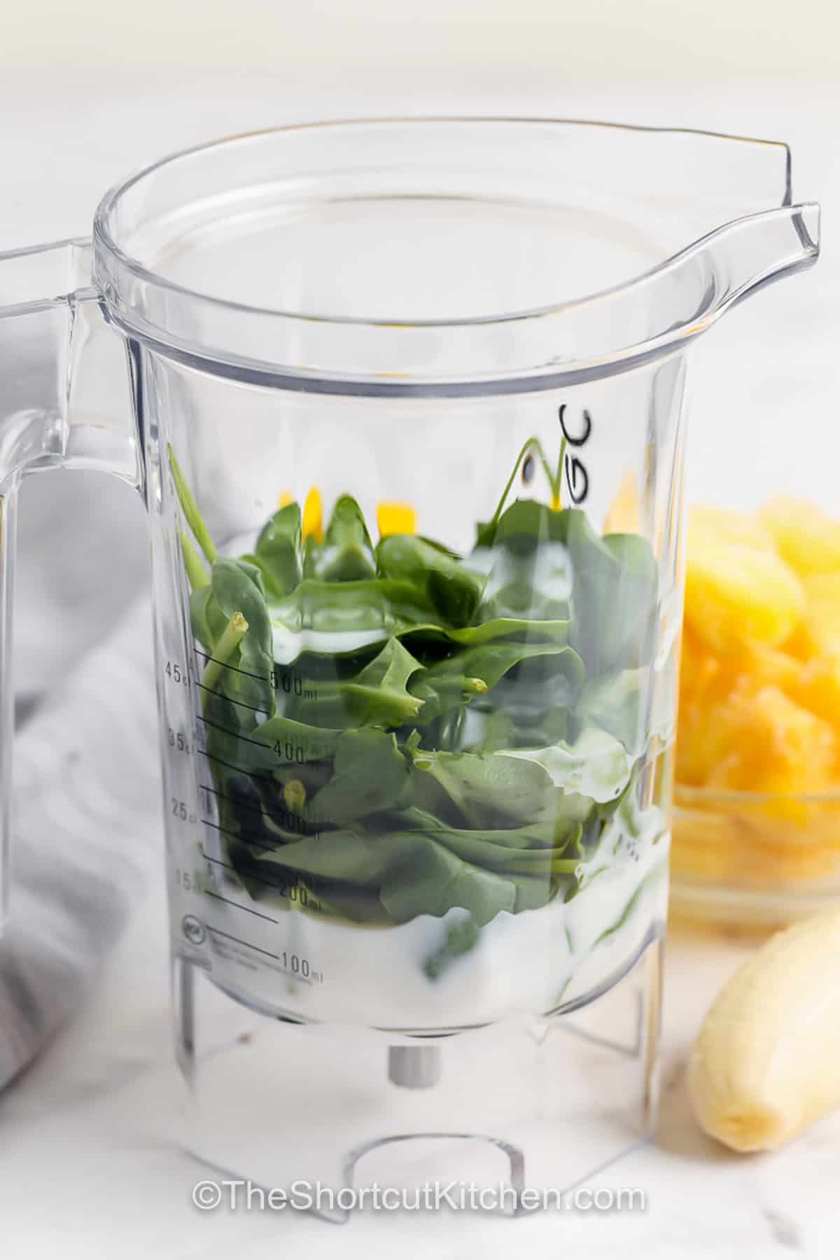 This creamy Green Smoothie Recipe features spinach, pineapple, banana, and vanilla yogurt for a refreshing, nutrient-packed breakfast smoothie that’s quick and easy to make. It’s simple to add in extras like nuts or seeds, ice for an extra frozen treat, or a little honey to make it even sweeter. Swap kale for spinach, or try using coconut cream or plant-based milk for a vegan twist. #theshortcutkitchen spinach in a blender to make Green Smoothie Recipe