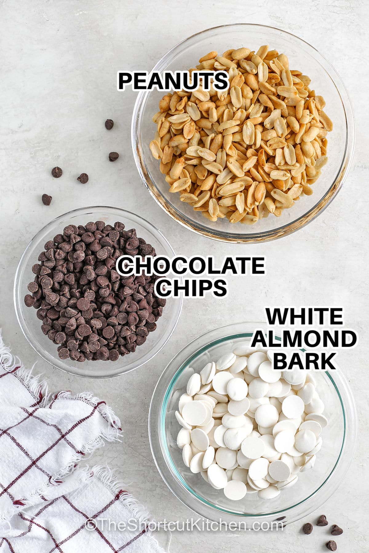 Crockpot peanut clusters are an easy Christmas candy made with roasted peanuts, semisweet chocolate chips, and creamy almond bark. This simple slow cooker recipe melts everything perfectly for sweet-salty clusters that harden beautifully. A great holiday treat for gifting, dessert trays, or make-ahead prepping. #theshortcutkitchen peanuts , chocolate chips , white almond bark with labels to make Crockpot Peanut Clusters