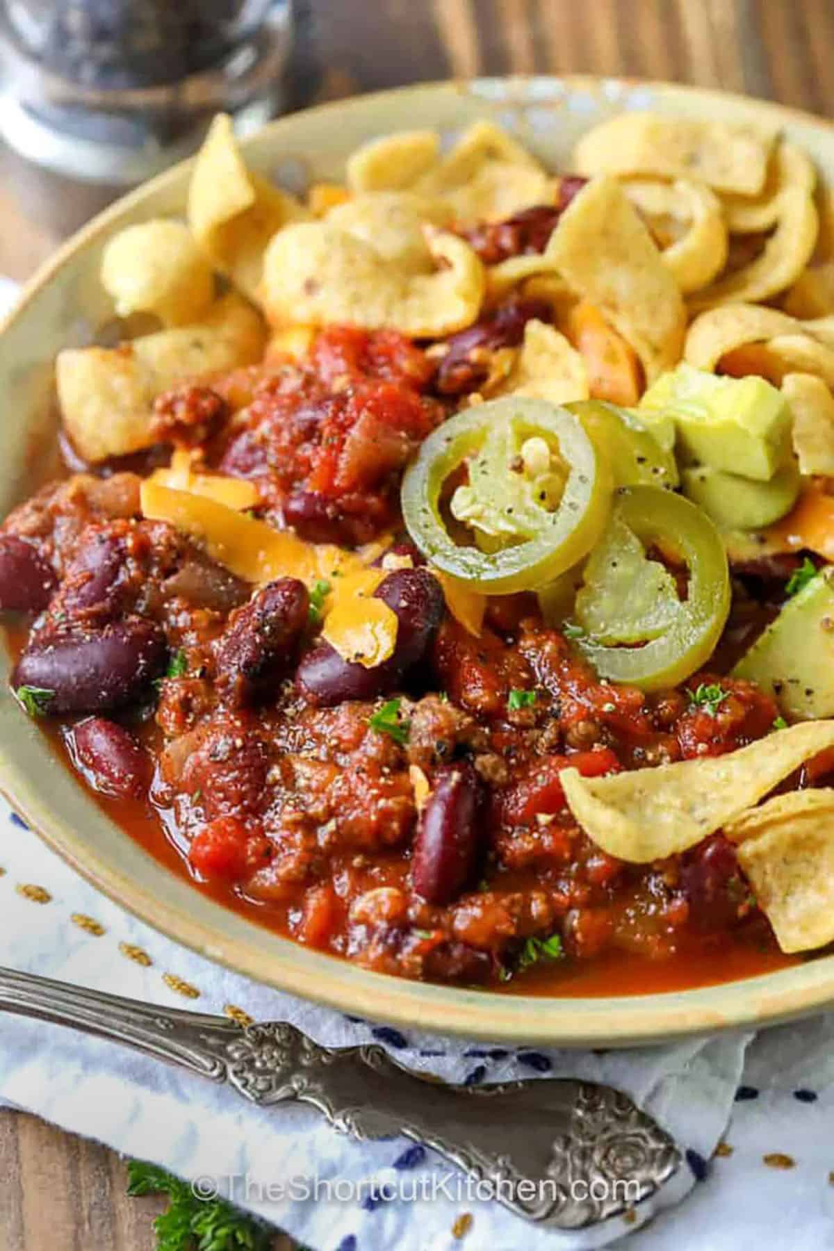 Easy crockpot chili is the ultimate cozy dinner made with ground beef and beans. Browning the meat with onion builds flavor, then the slow cooker does the rest with crushed tomatoes, diced tomatoes with chilies, and chili powder. This crockpot chili recipe is thick, comforting, and perfect for leftovers, plus it freezes well for busy nights. #theshortcutkitchen plated Easy Crockpot Chili with jalapeños