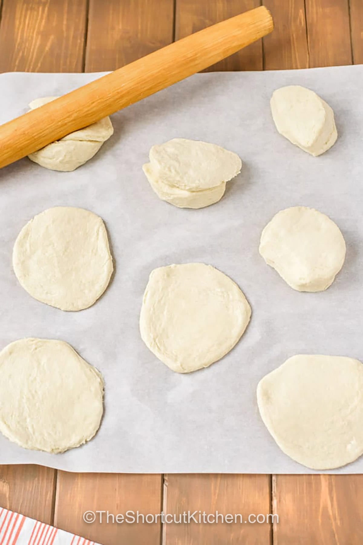 Bacon cream cheese biscuits are stuffed biscuits that disappear fast. Cream cheese, bacon, parmesan, green onion, and garlic powder create a creamy filling, while shredded cheddar melts on top during baking. Perfect for holiday mornings, potlucks, and game day. Store leftovers in the fridge and warm back up in the air fryer for the best flaky texture and melty center. #theshortkitchen rolling out dough to make Bacon Cream Cheese Biscuits