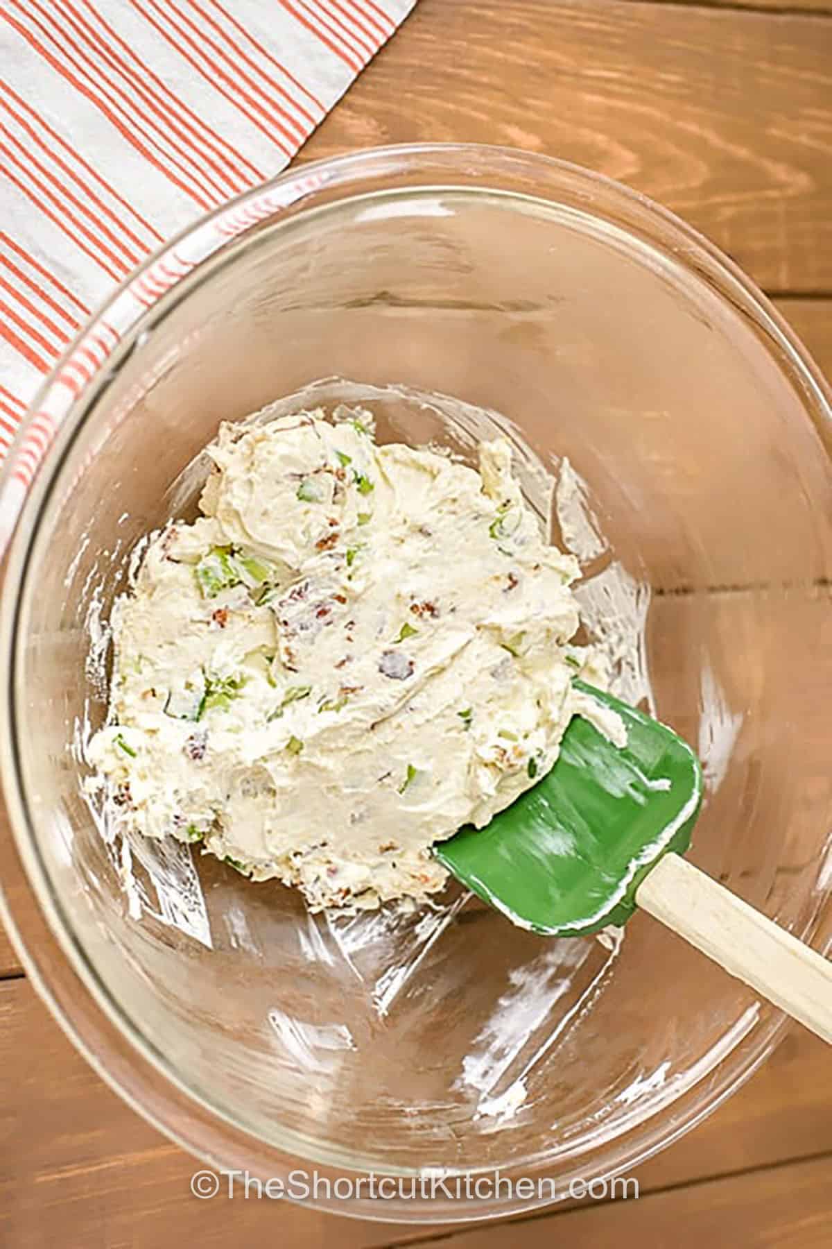 Turn canned dough into bacon cream cheese biscuits, also known as biscuit bombs. Each biscuit is rolled, stuffed with bacon and cream cheese filling, sealed, topped with cheddar, and baked. The flavor is savory, cheesy, and perfect for parties or a quick breakfast. Make ahead, refrigerate leftovers, and reheat in the air fryer for a crisp finish. #theshortcutkitchen mixed ingredients for filling to make Bacon Cream Cheese Biscuits