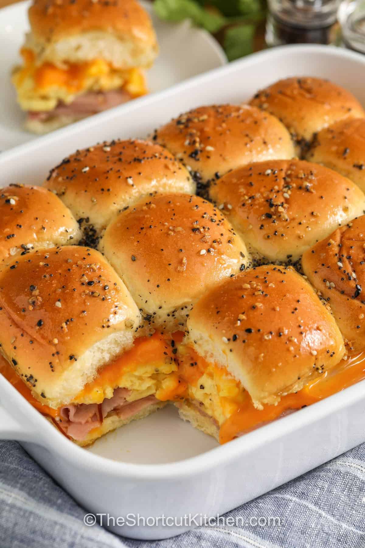 Make these breakfast sliders for busy mornings or weekend brunch. Hawaiian rolls stay soft while eggs, ham, and cheese warm through in the oven. The butter glaze with everything bagel seasoning adds big flavor and golden tops. Slice into individual ham egg and cheese breakfast sliders and serve warm, or meal prep and reheat for quick grab-and-go breakfasts. #theshortcutktichen baking dish with cheesy Breakfast Sliders