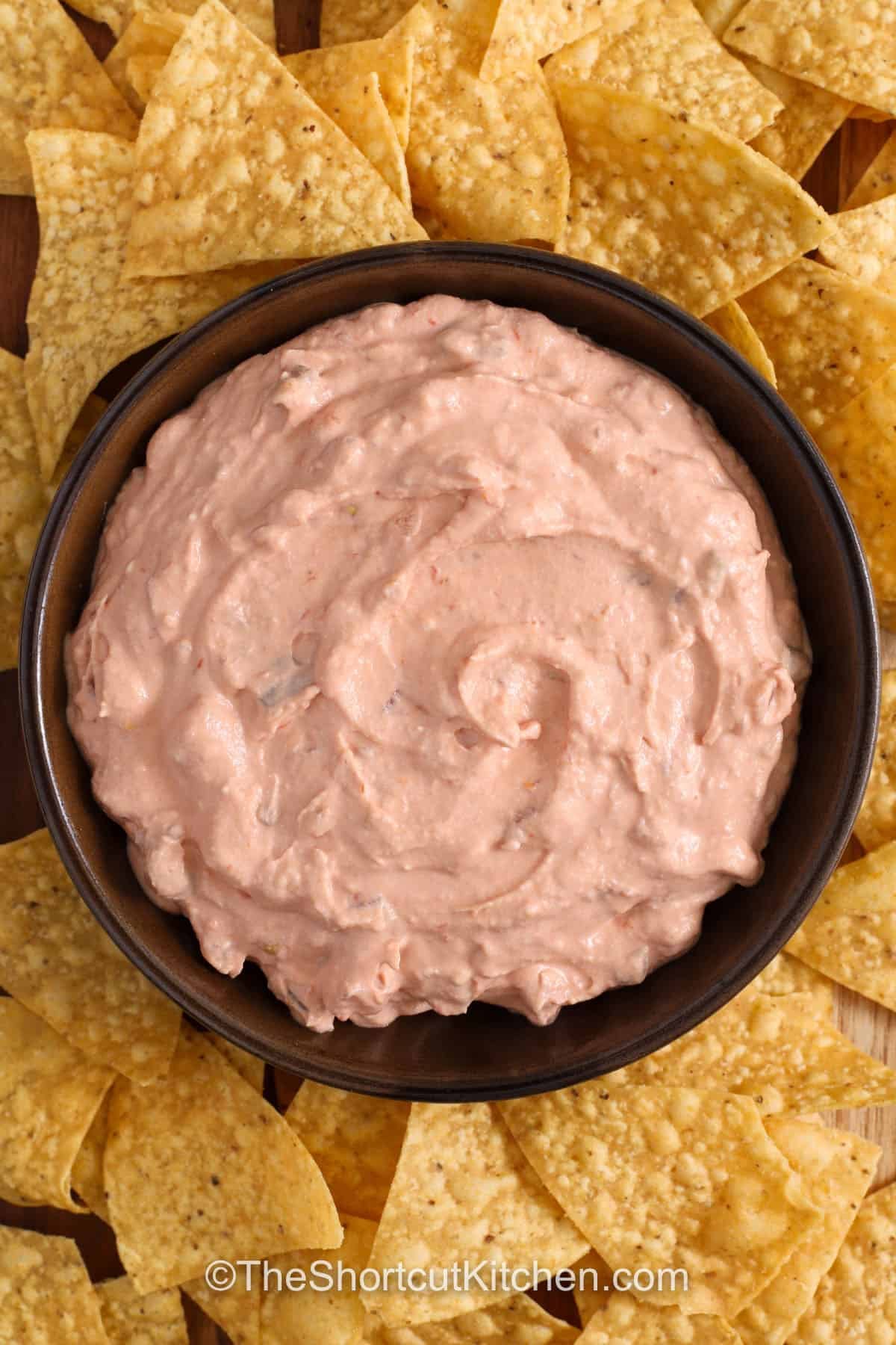 Cream Cheese Salsa Dip is a quick and creamy snack dip made from pantry staples. Fully softened cream cheese helps everything blend smoothly, while a short chill in the fridge creates the right thickness. A chunky salsa gives the best scoopable texture. Top with shredded cheddar cheese and green onions for extra flavor. If you enjoy spice, stir in diced jalapeños. Serve this easy salsa dip with chips, crackers, or fresh veggies for sharing. #theshortcutkitchen top view of Cream Cheese Salsa Dip in a bowl
