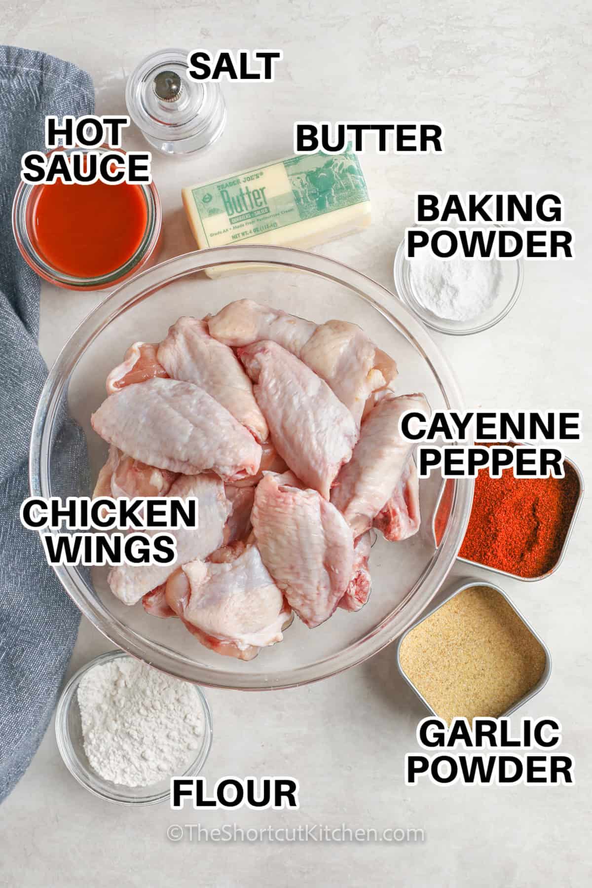 Make baked buffalo wings that come out crispy, loaded with sauce, and sure to please any crowd. The secret is drying the wings and chilling after coating so the skin bakes up crunchy in the oven. Toss in a simple butter hot sauce for classic Buffalo chicken wings flavor. Serve right away with celery and ranch. Great for game day, movie nights, and easy entertaining. #theshortcutkitchen hot sauce, salt, butter, cayenne pepper, garlic powder, chicken wings, baking powder, and flour with labels to make Oven Baked Chicken Wings