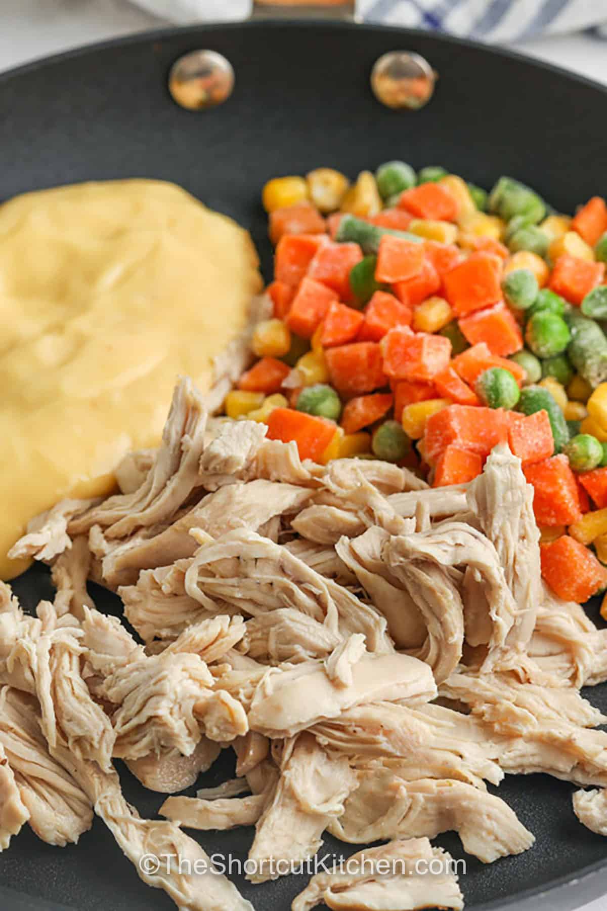 If you love pot pie but want the easiest version, make mini chicken pot pies in a muffin tin. Crescent roll cups hold a creamy chicken filling made with condensed cream of chicken soup, chopped cooked chicken, and frozen mixed vegetables. Bake until golden brown for individual chicken pot pies that feel special but take almost no effort. Great for parties and weeknight dinners. #theshortcutkitchen adding ingredients to pan to make filling for Mini Chicken Pot Pies