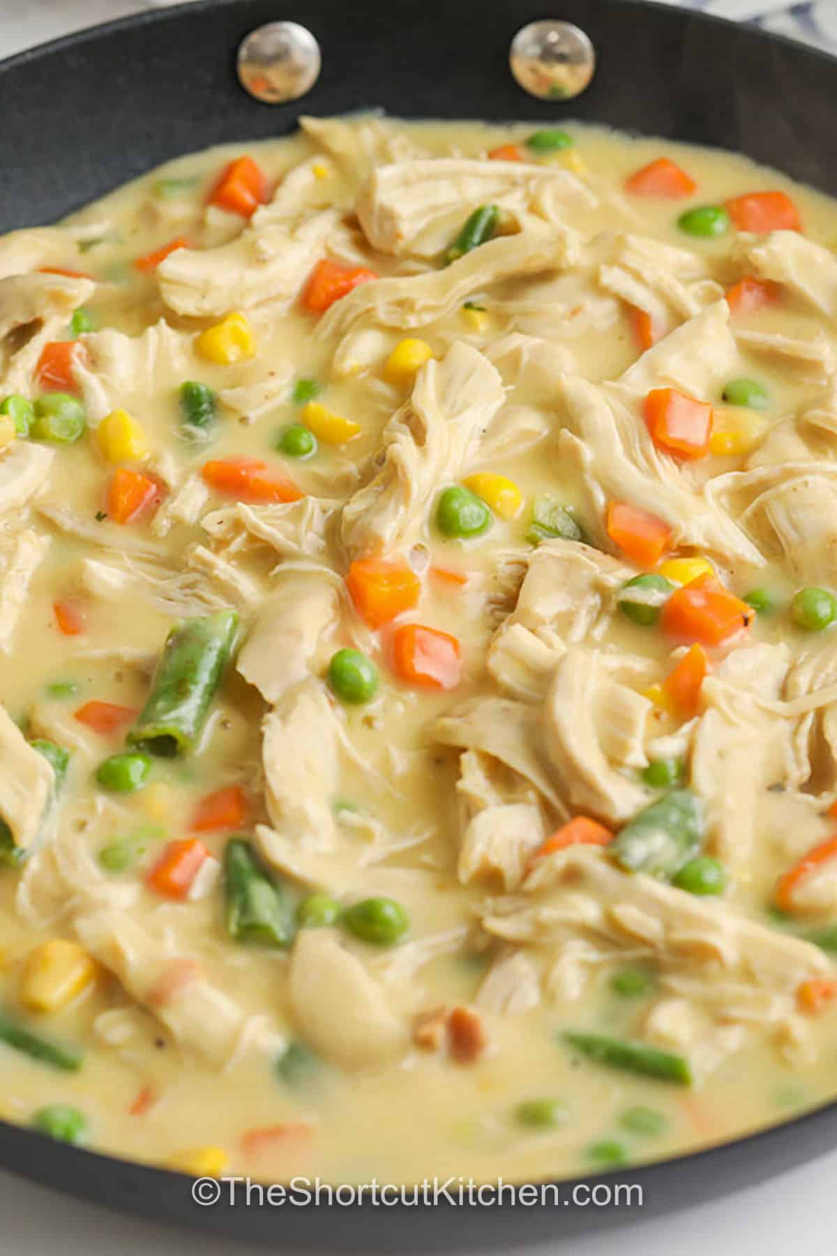 Turn classic comfort food into bite-sized mini chicken pot pies. Crescent rolls create a flaky crust in a muffin tin, while the filling uses cooked chicken, frozen mixed vegetables, and cream of chicken soup for a creamy pot pie flavor without extra steps. These chicken pot pie bites are easy to serve, kid-friendly, and perfect for meal prep since leftovers store and reheat easily. #theshortcutkitchen filling for Mini Chicken Pot Pies in a pan