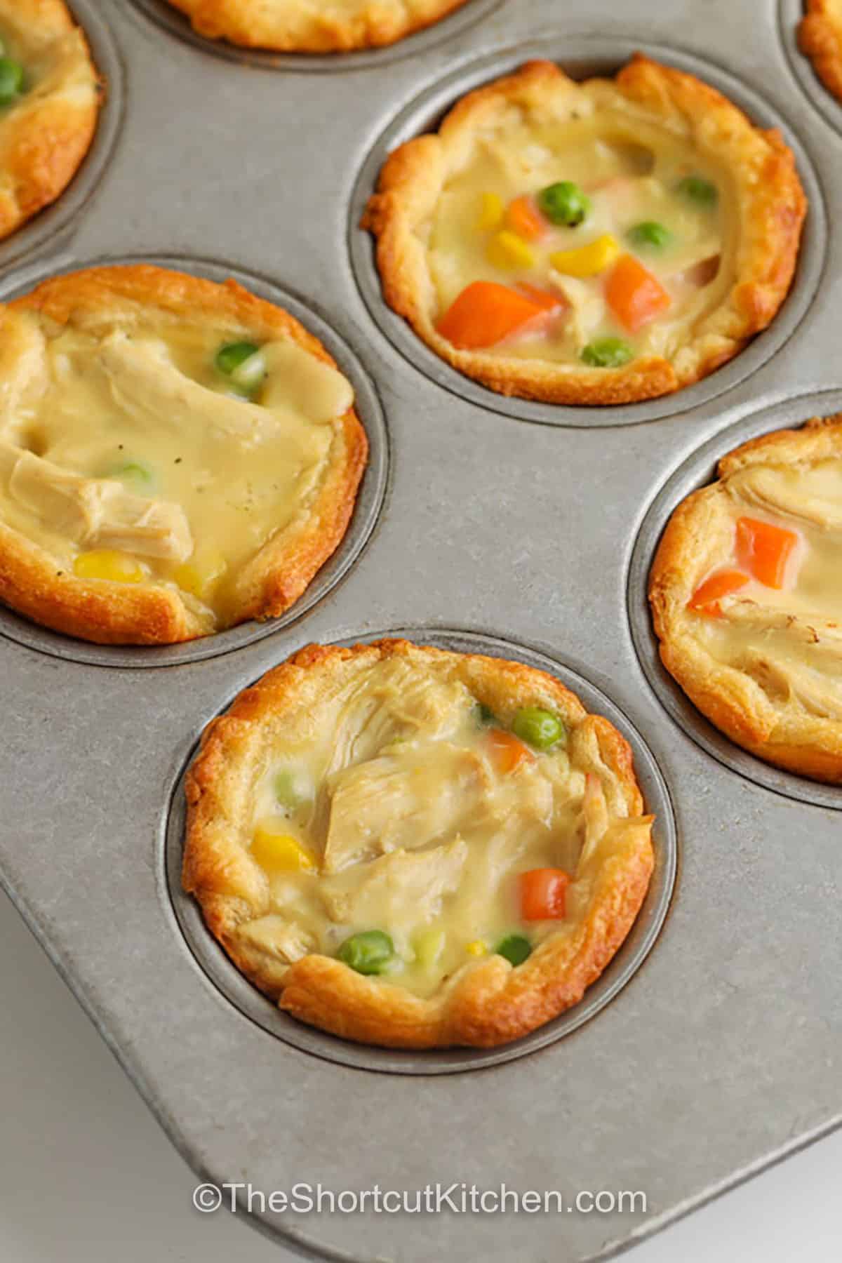 Mini chicken pot pies are a fast way to get cozy flavor on the table. The filling is cooked chicken, frozen mixed vegetables, and cream of chicken soup simmered briefly, then spooned into crescent roll cups in a muffin tin. Bake until golden and serve as individual chicken pot pies. They reheat well and can be frozen for quick snacks and lunches. #theshortcutkitchen Mini Chicken Pot Pies in a muffin tin