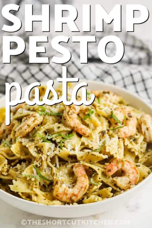 Make Shrimp Pesto Pasta with simple pantry ingredients you can keep on hand. Cook pasta, sauté diced onion, warm up some cooked shrimp, then toss everything together with pesto sauce and lemon zest. Add a little reserved pasta water to create a savory pesto shrimp pasta sauce without any extra steps. Top with parmesan and basil if you want it fancy. It’s a quick, classy shrimp pasta for any night. #theshortcutkitchen close up of plated Shrimp Pesto Pasta with a title