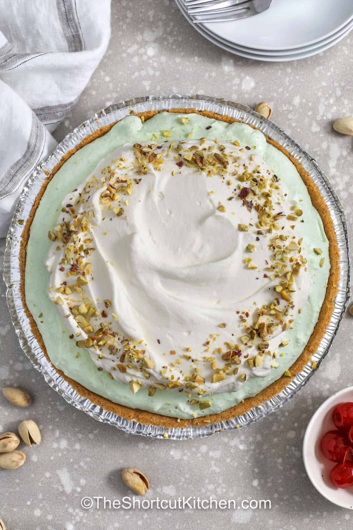 If you love easy desserts, pistachio pie is a must. This no bake pistachio pie combines instant pistachio pudding, cold milk, cream cheese, and whipped topping for a fluffy pistachio cream pie feel without baking. Use a premade graham crust to save time, chill for a few hours, and serve with pistachios or cherries. Perfect for spring celebrations and potlucks. #theshortcutkitchen top view of Pistachio Pie