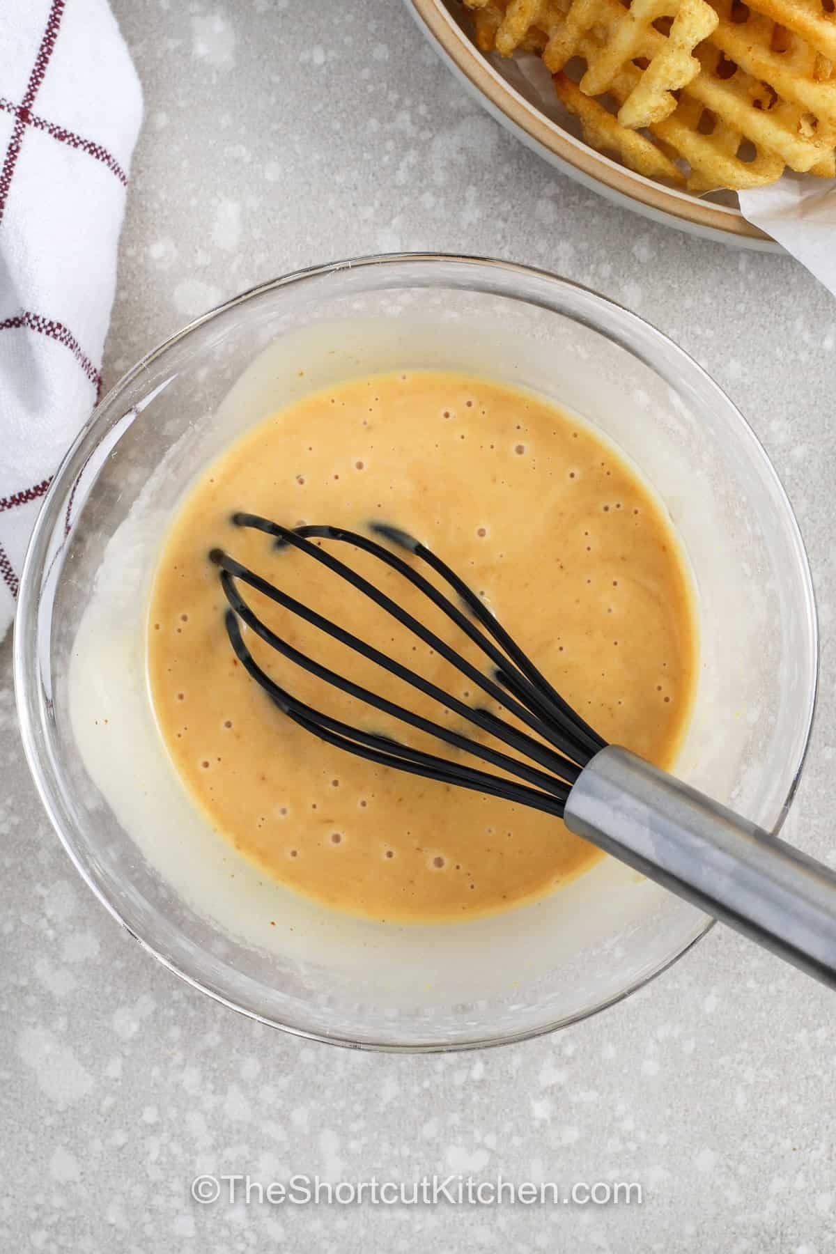 Chick-Fil-A sauce recipe fans can enjoy drive-thru food at home with this rich and creamy dip made with just a few simple ingredients. This easy Chick-Fil-A sauce recipe has the perfect balance of honey mustard and BBQ flavor, making it great for dipping fries, chicken tenders, or even fresh veggies. It stirs together smoothly and works as a spread for wraps and burgers, too. Make a batch to keep in the fridge and enjoy that classic flavor anytime you like. #theshortcutkitchen whisking ingredients to make chick-fil-a sauce recipe