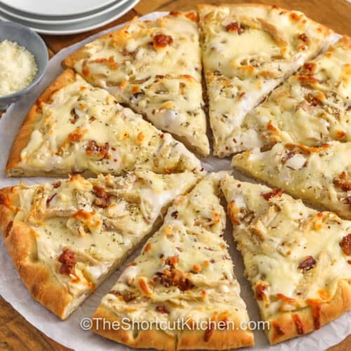 Chicken Alfredo Pizza cut into slices on a wooden cutting board