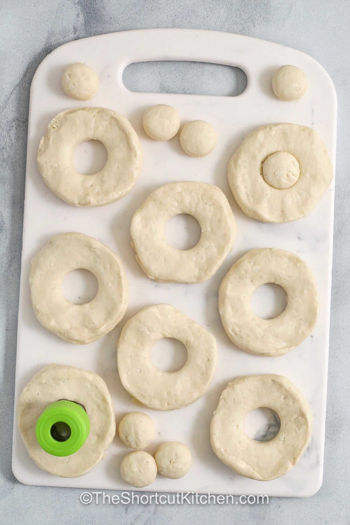 Make cinnamon sugar donuts at home without yeast using this easy donut recipe. Canned biscuits fry up fluffy, then get brushed with melted butter so cinnamon sugar coats every bite. Use the cut-out centers for donut holes and serve warm. Add a simple vanilla glaze or chocolate glaze for variety, plus air fryer donuts directions. #theshortcutkitchen uncooked donuts on a cutting board