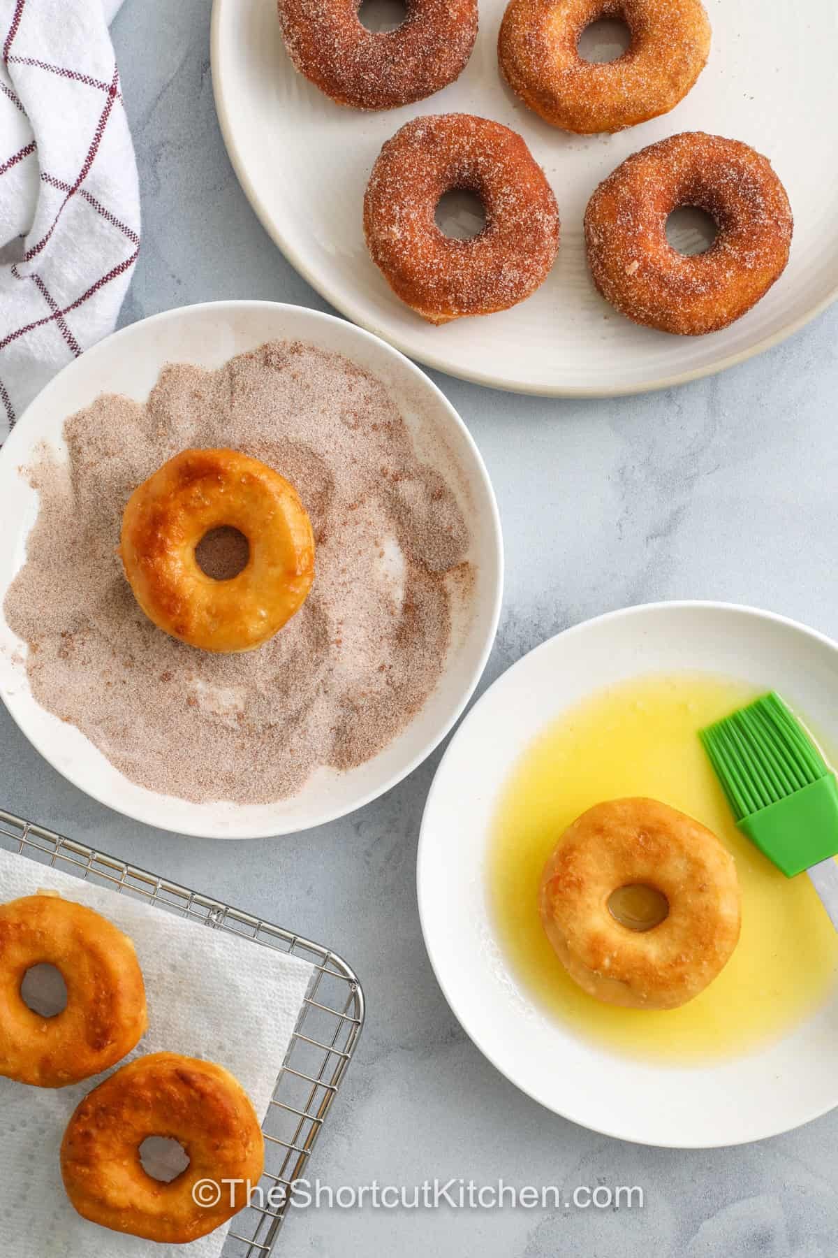 Turn a can of biscuits into golden canned biscuit donuts with this easy donut recipe. Press, cut, fry, drain, then brush with butter and roll in cinnamon sugar for that classic donut shop flavor. Make mini donut holes from the centers, too. Includes glaze variations and an air fryer donuts option, perfect for quick weekend breakfasts. #theshortcutkitchen donuts in butter and in sugar