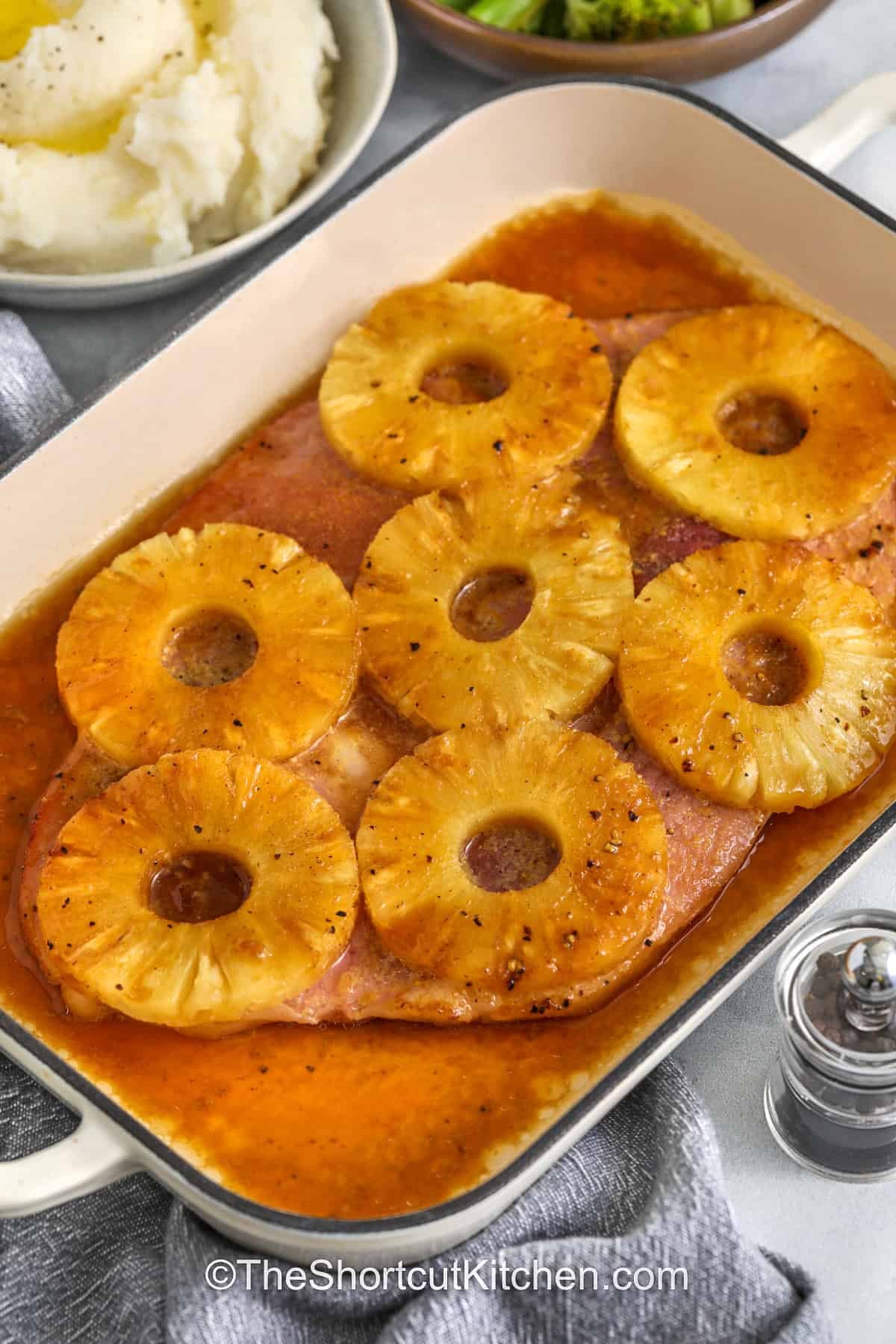 This ham steak recipe pairs pineapple with a brown sugar glaze to make a simple yet impressive dinner. The ham bakes in a sauce of Dijon mustard, soy sauce, garlic, and black pepper to enhance the meat's flavor. Pineapple rings add sweetness and help keep the ham tender while baking. This dish works well for family dinners or smaller holiday meals. Serve it with classic sides like mashed potatoes and roasted vegetables for a complete and satisfying dinner. #theshortcutkitchen juicy Ham Steak baked with pineapple rings and glaze