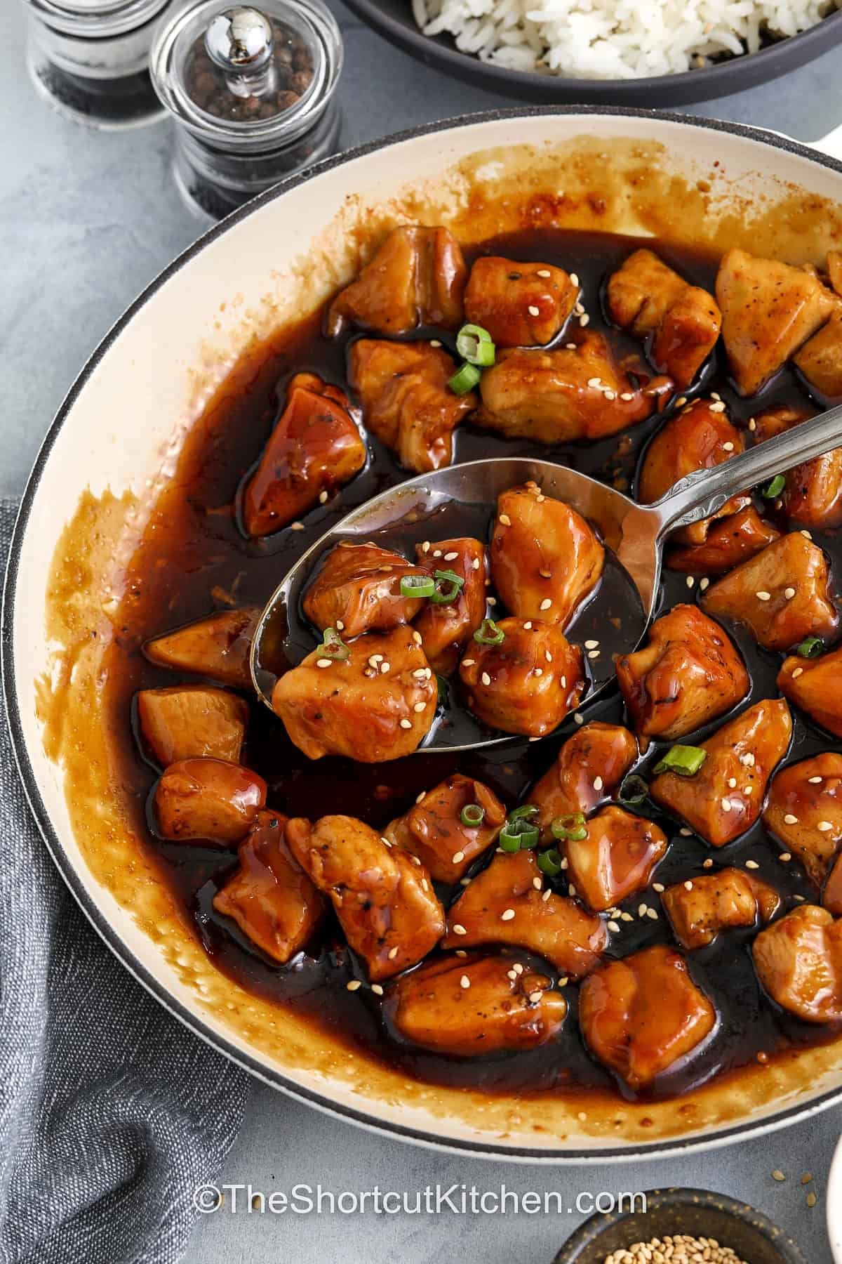 Honey teriyaki chicken is a sweet and savory chicken recipe made in one skillet. Bite sized chicken pieces cook in a pan and are finished in a glossy honey teriyaki sauce made with bottled teriyaki, garlic, and rice vinegar. The rich glaze coats every piece of chicken and brings classic takeout-style flavor to a homemade dinner. Serve it over rice or alongside vegetables for a balanced plate made with simple ingredients and bold flavor. #theshortcutkitchen taking a spoonfull of Honey Teriyaki Chicken out of the pan