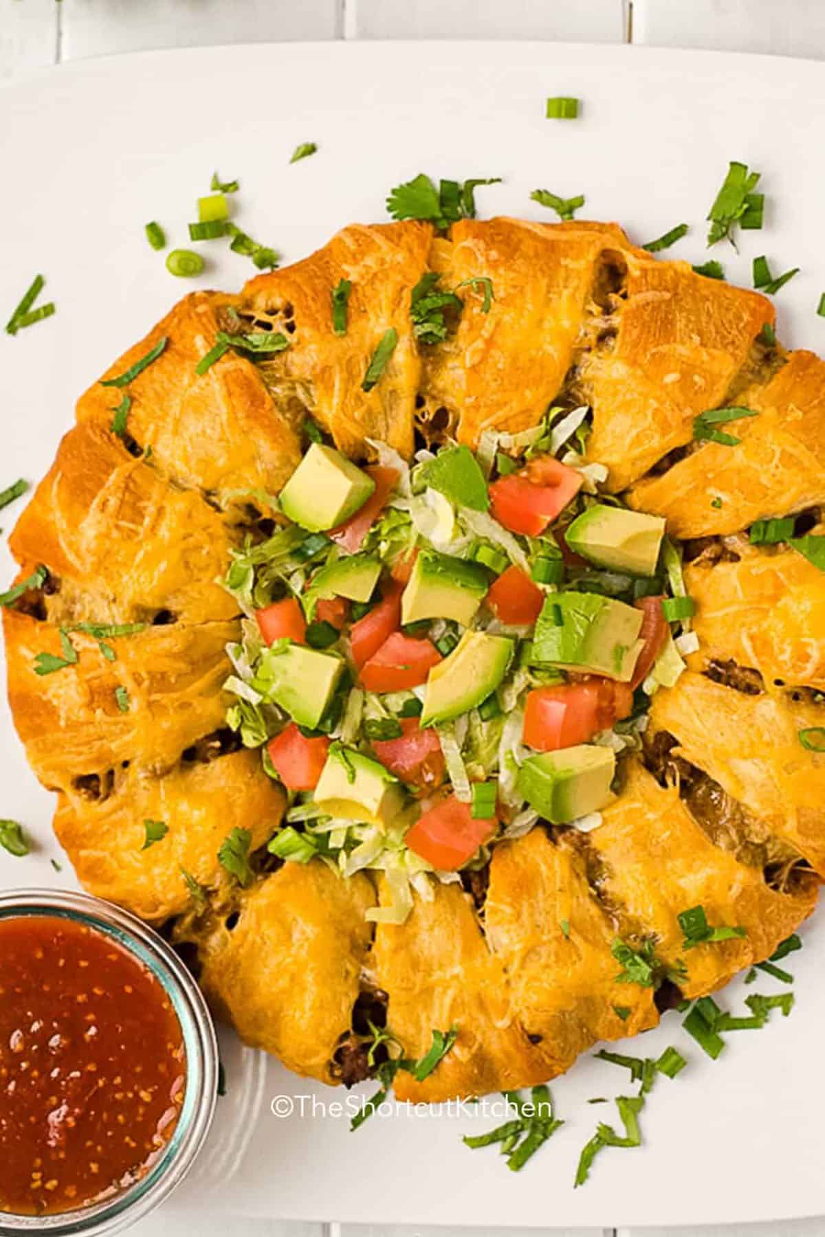 If you need an easy dinner with ground beef, this taco ring recipe is a great pick. It combines taco meat, cheddar cheese, and crescent rolls in a baked ring that is crisp on the outside and cheesy inside. This is a family-friendly shortcut meal that works well for busy weeknights, potlucks, or casual entertaining with lots of topping options. #theshortcutkitchen Taco Ring with dip